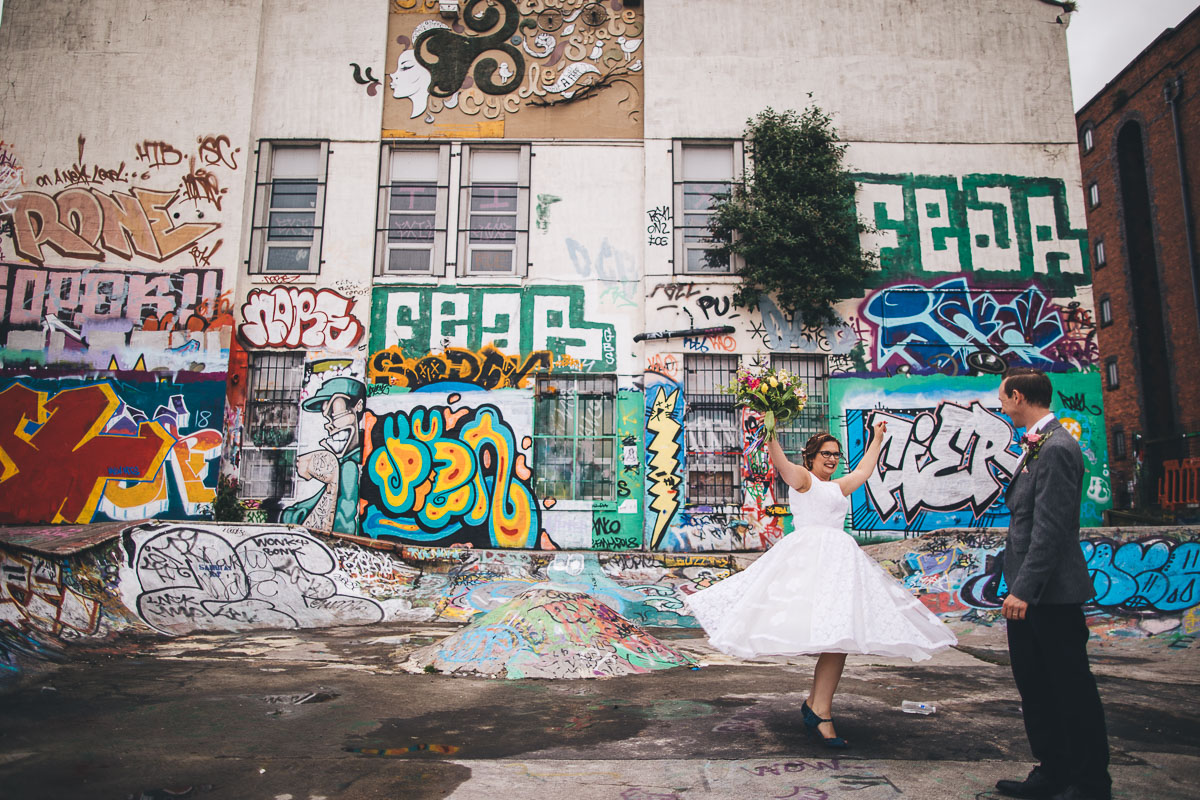 bride twirls in front of graffiti wall