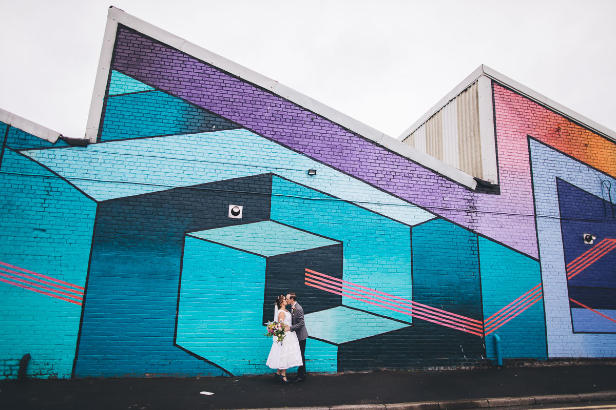 wedding portrait in front of bright colourful geometric wall