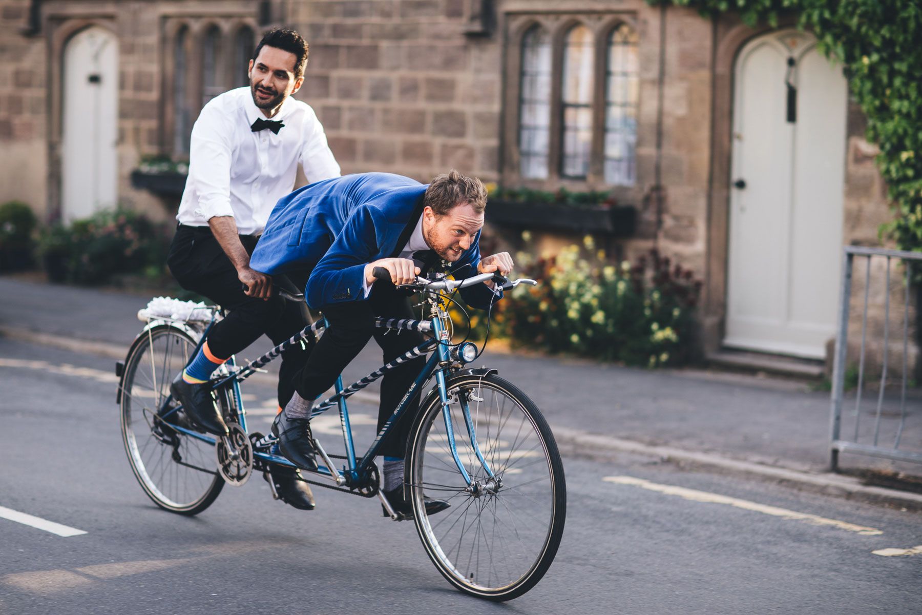 two groomsmen on tandem bike in a manchester wedding