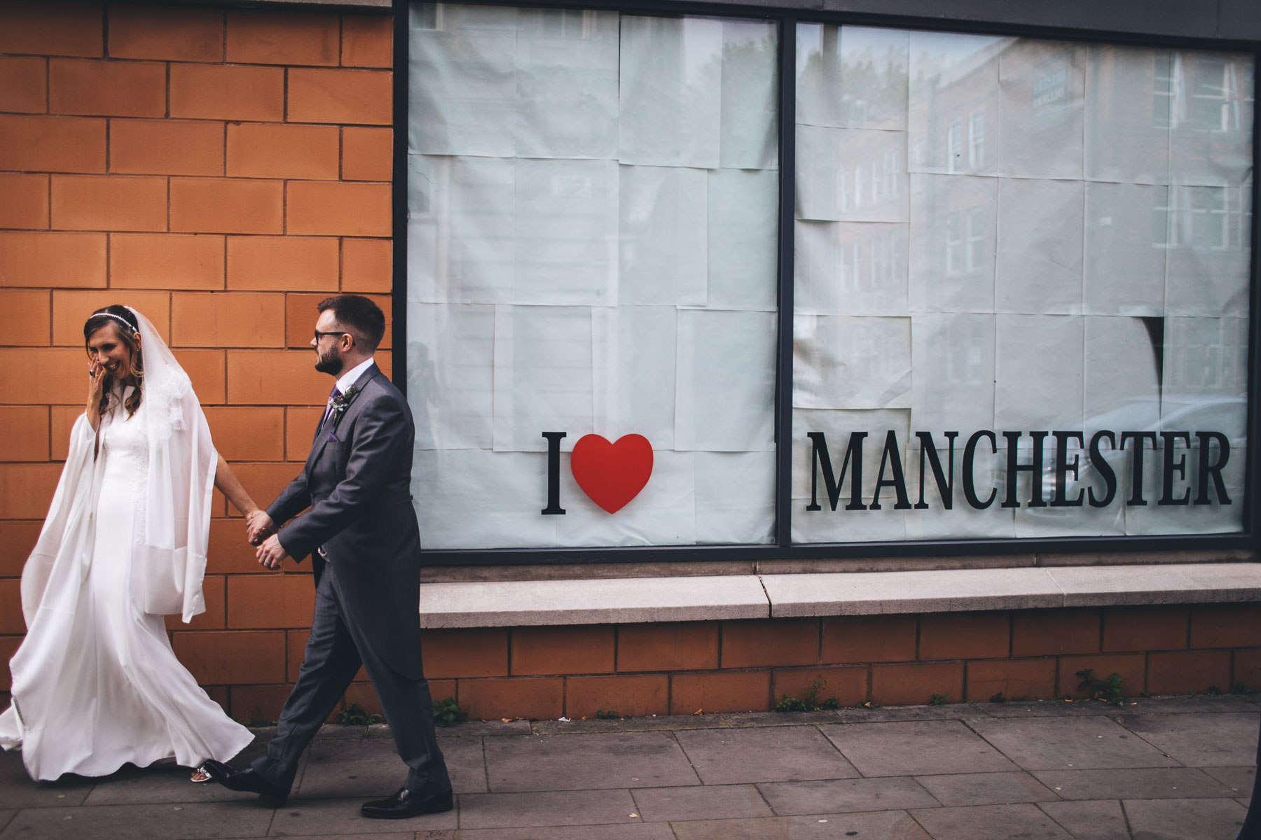 newly weds walk past an i love Manchester sign