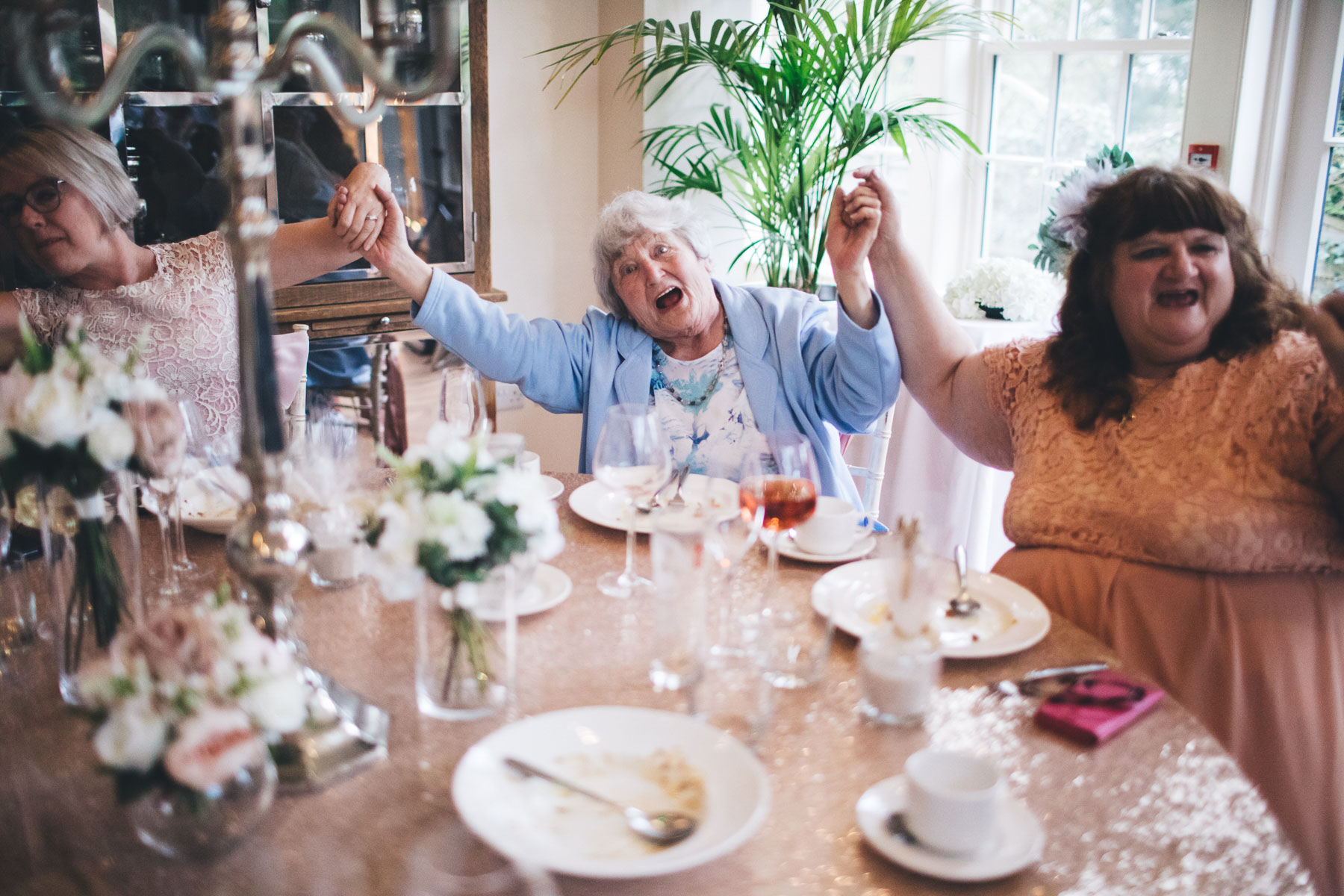 grandma holding hands up singing along during the wedding breakfast