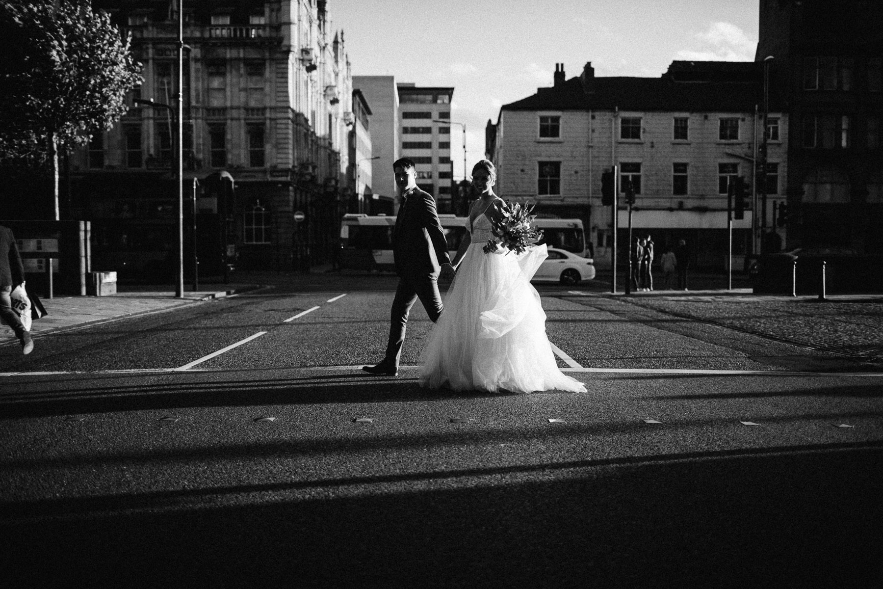 couple walk across road in manchetser late sun