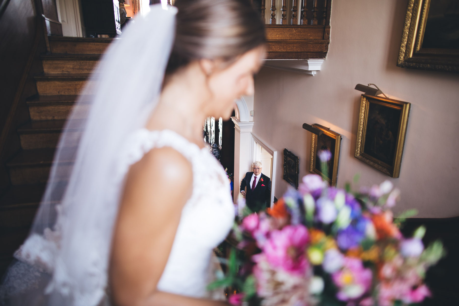 father waits at the bottom of the stairs to see his daughter in her wedding dress