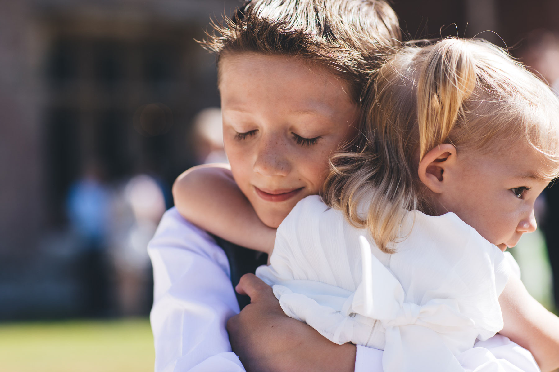 boy hugs his sister who is the flower girl at the wedding