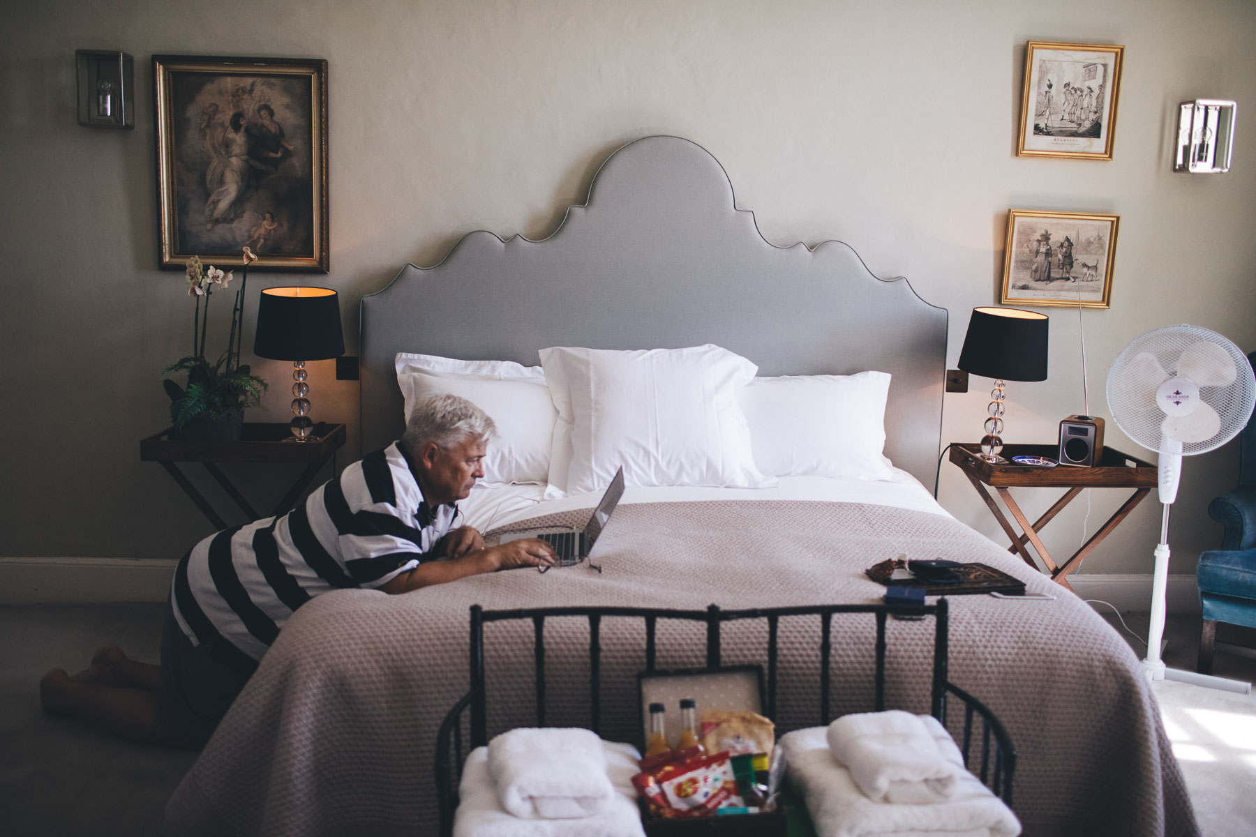 father on his laptop on the bed in their hotel room before the wedding