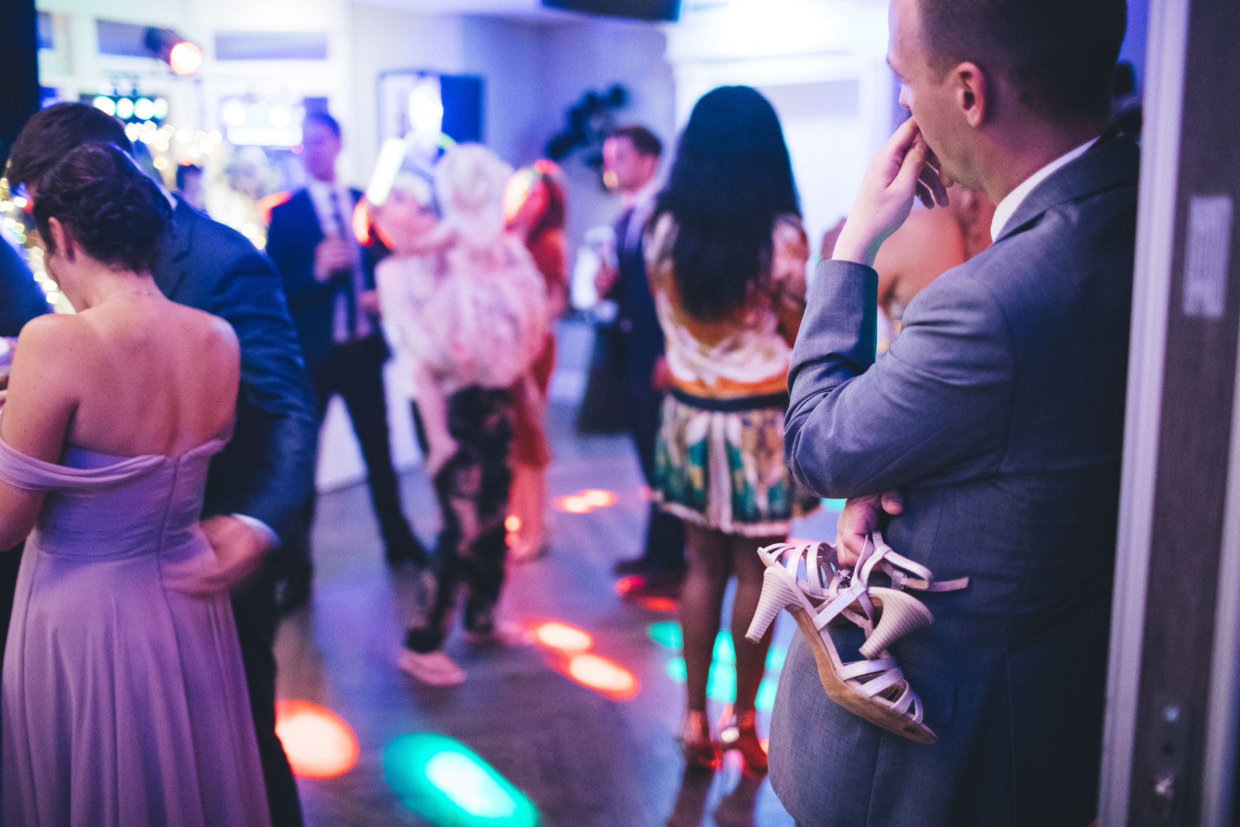 guy holds girls shoes at the side of the dance floor