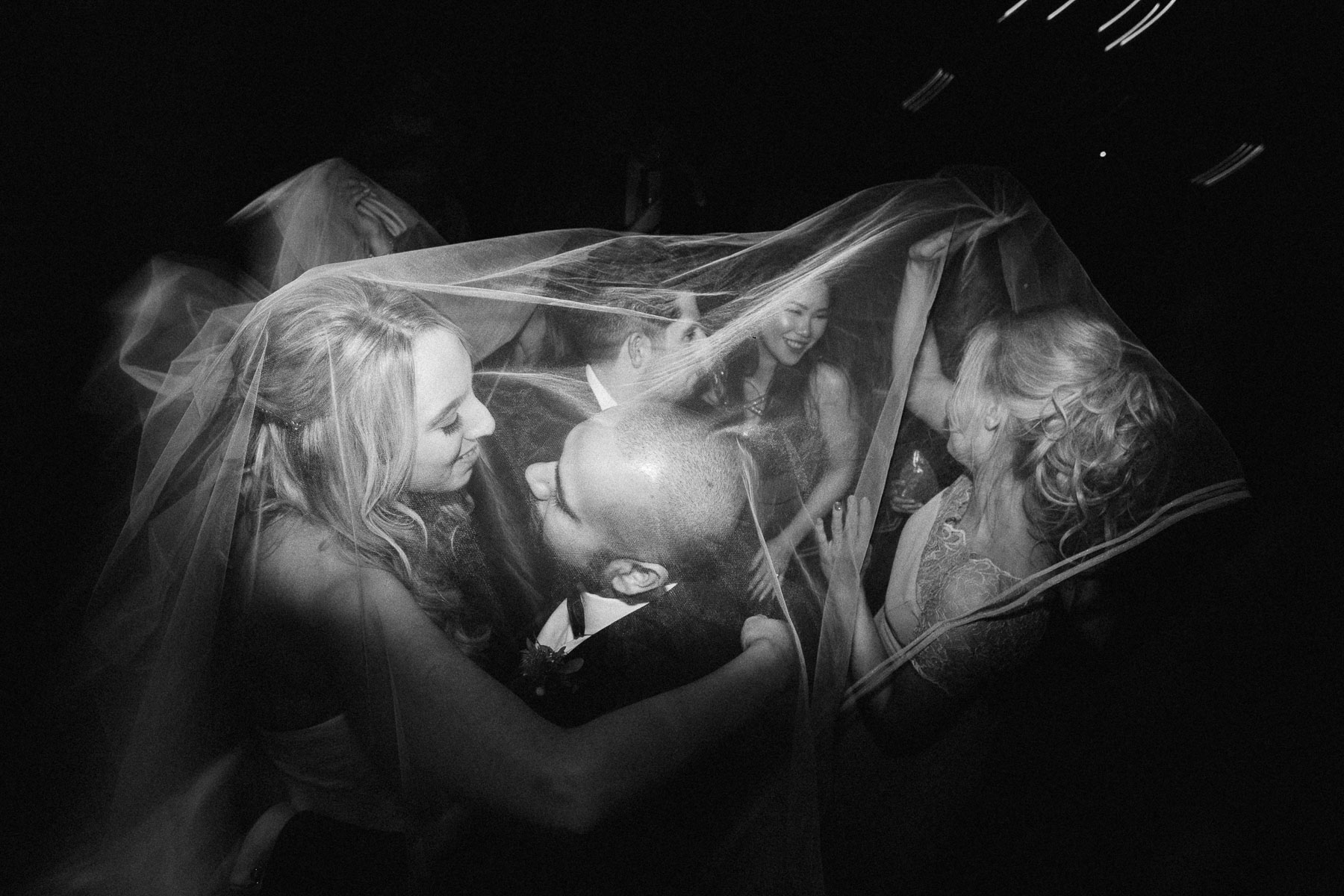 brides and guests dance together under her veil
