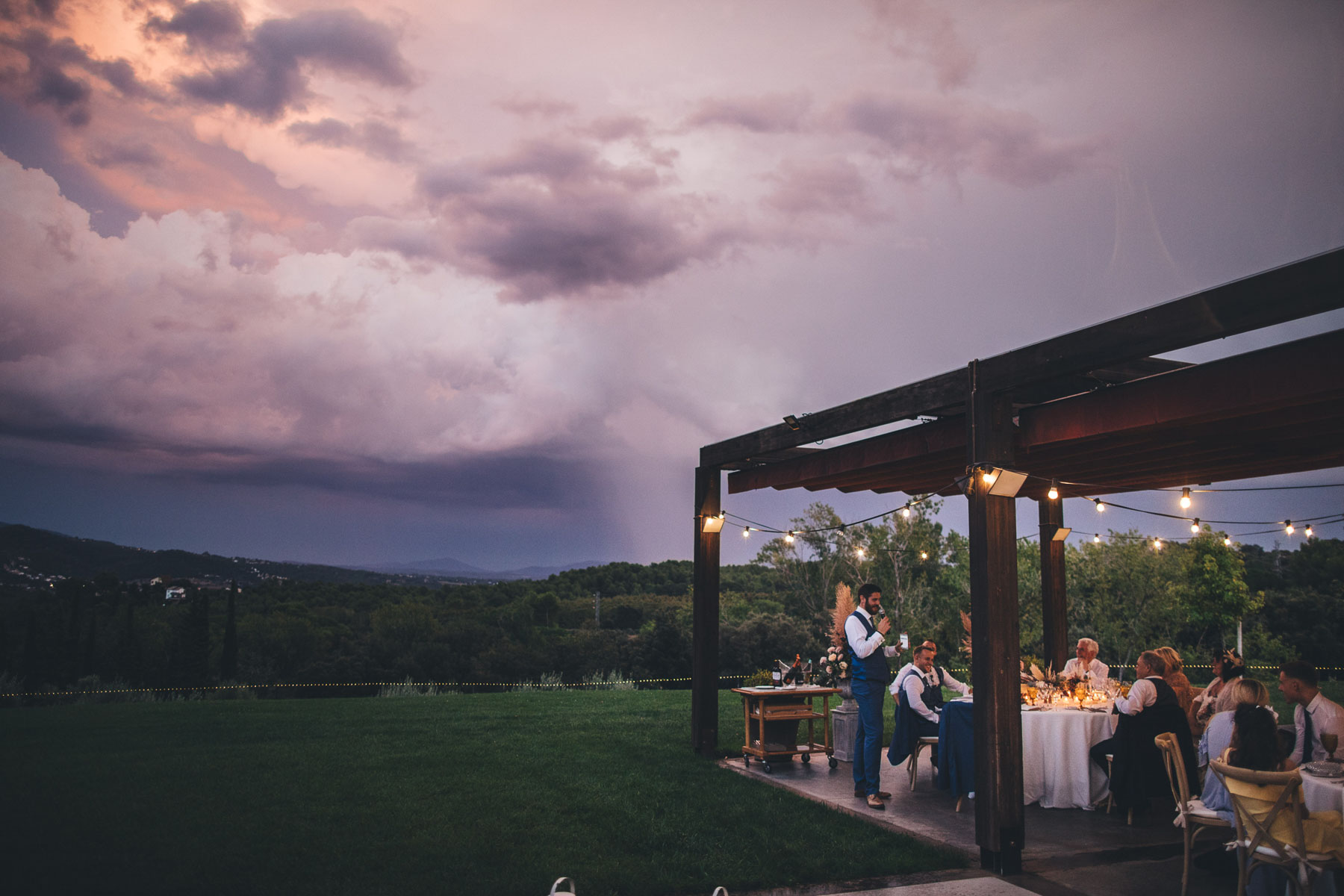 best man gives speech underneath an amazing sunset in spain