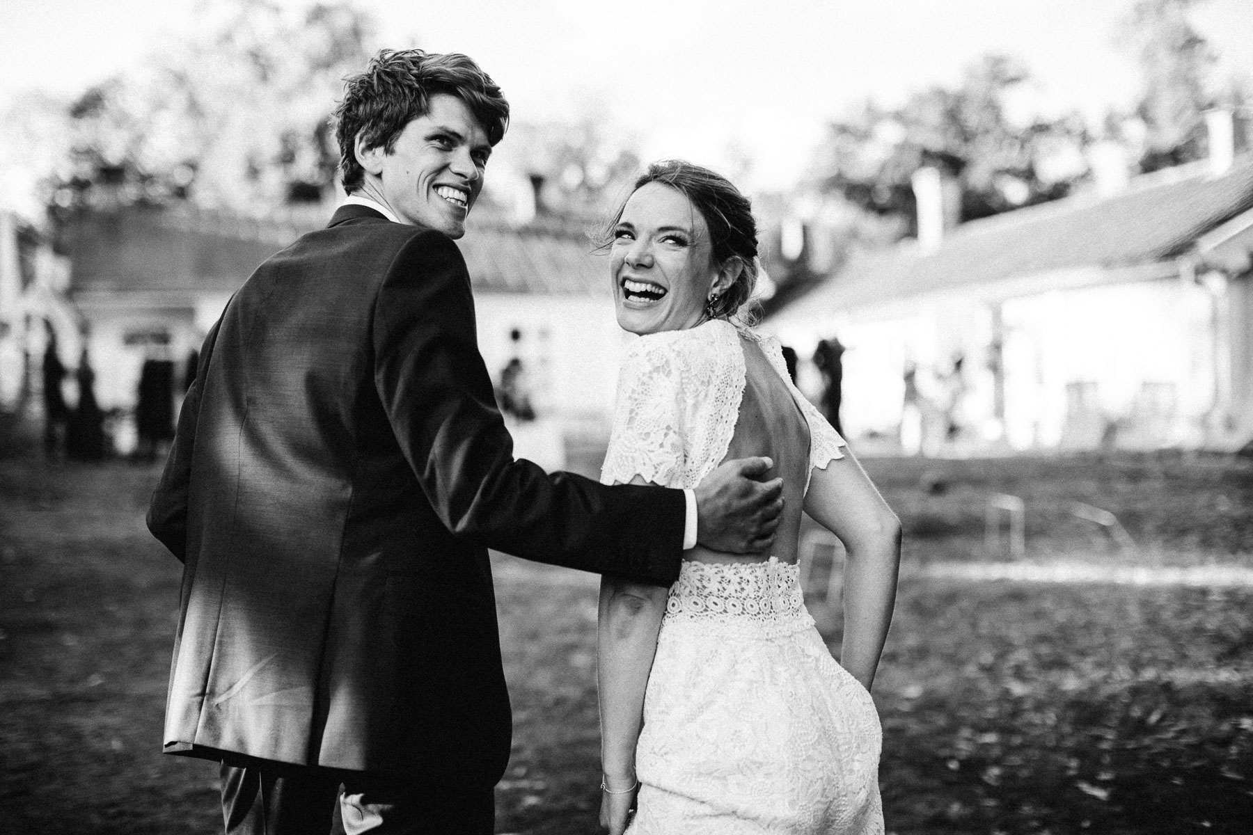 bride and groom look back over their shoulders with big beautiful smiles on their faces
