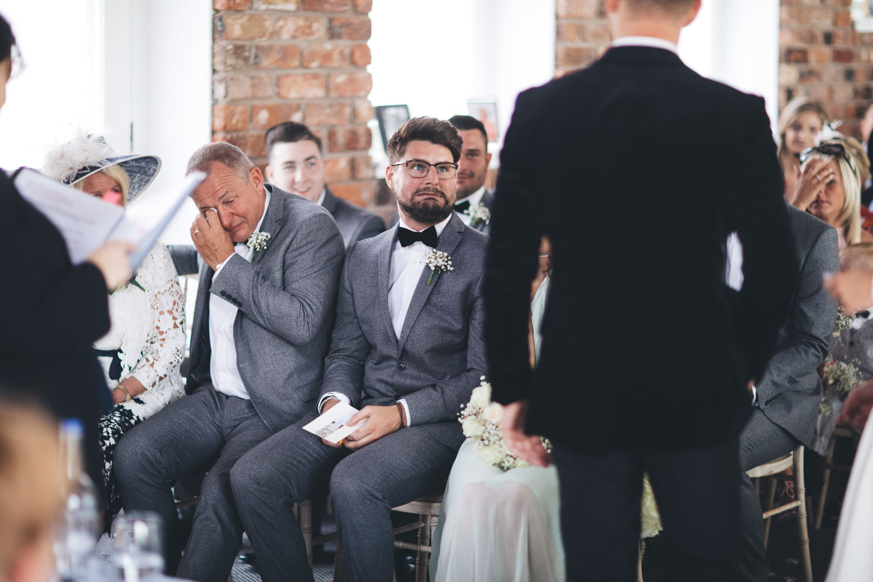best man pulls silly face when asked for the wedding rings while father cries next to him