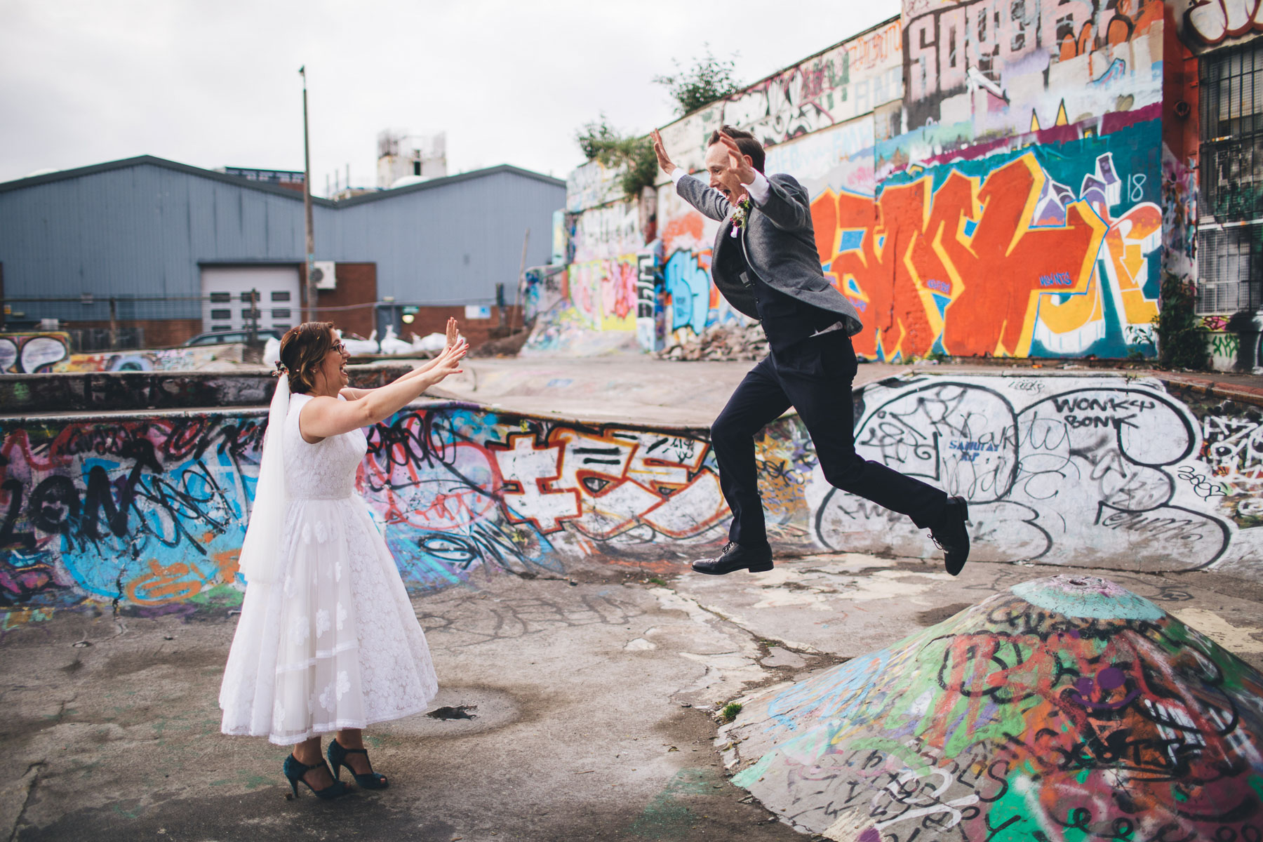 groom jumps off a mound towards his bride, both of them have their hands in the air