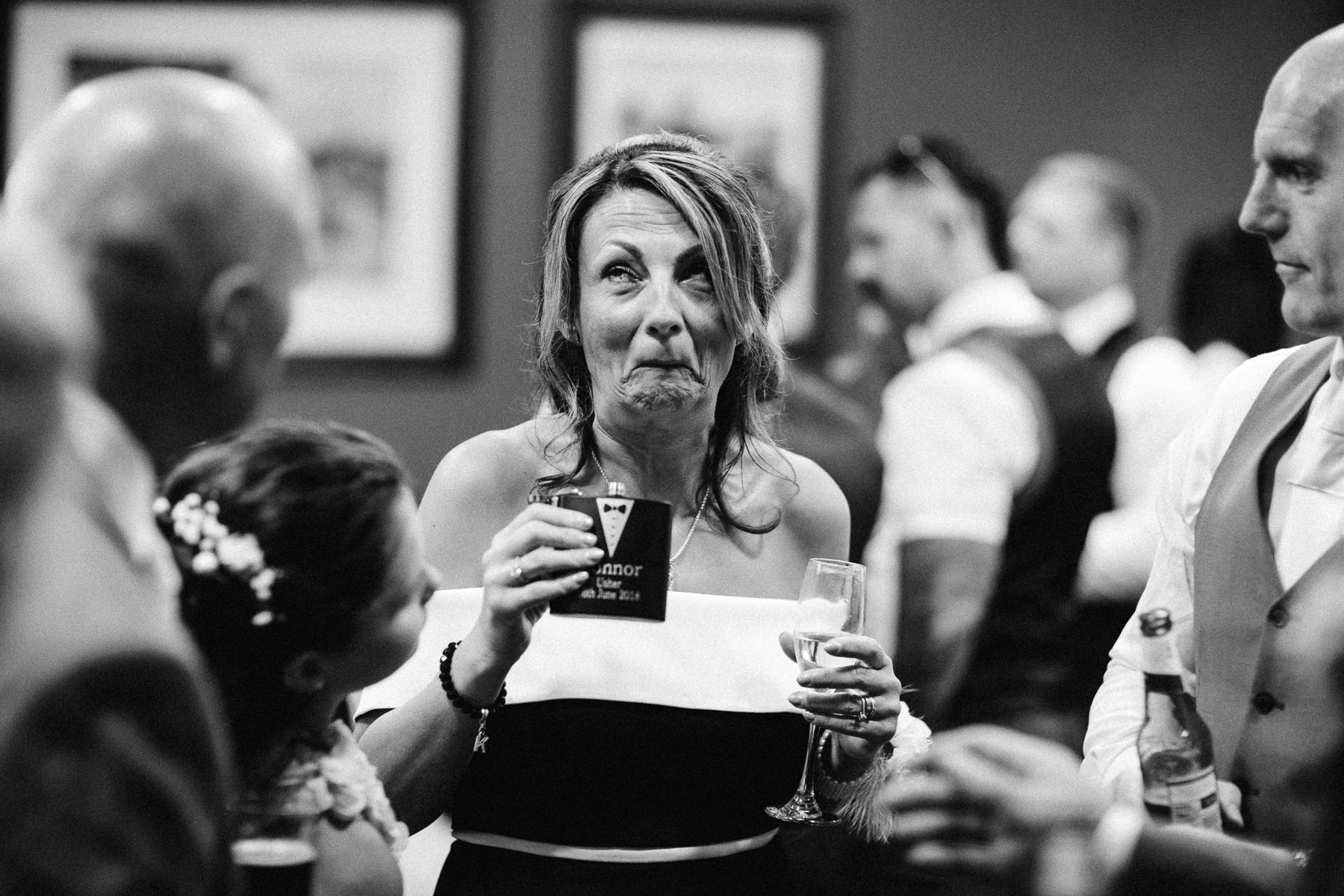 woman pulls funny face after drinking booze from a hip flask