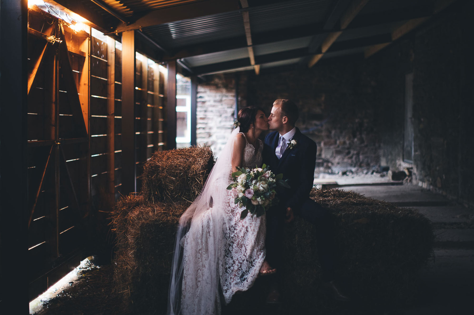 couple kiss in barn conversion for wedding venue
