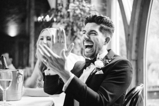 groom laughs and claps during the wedding speeches