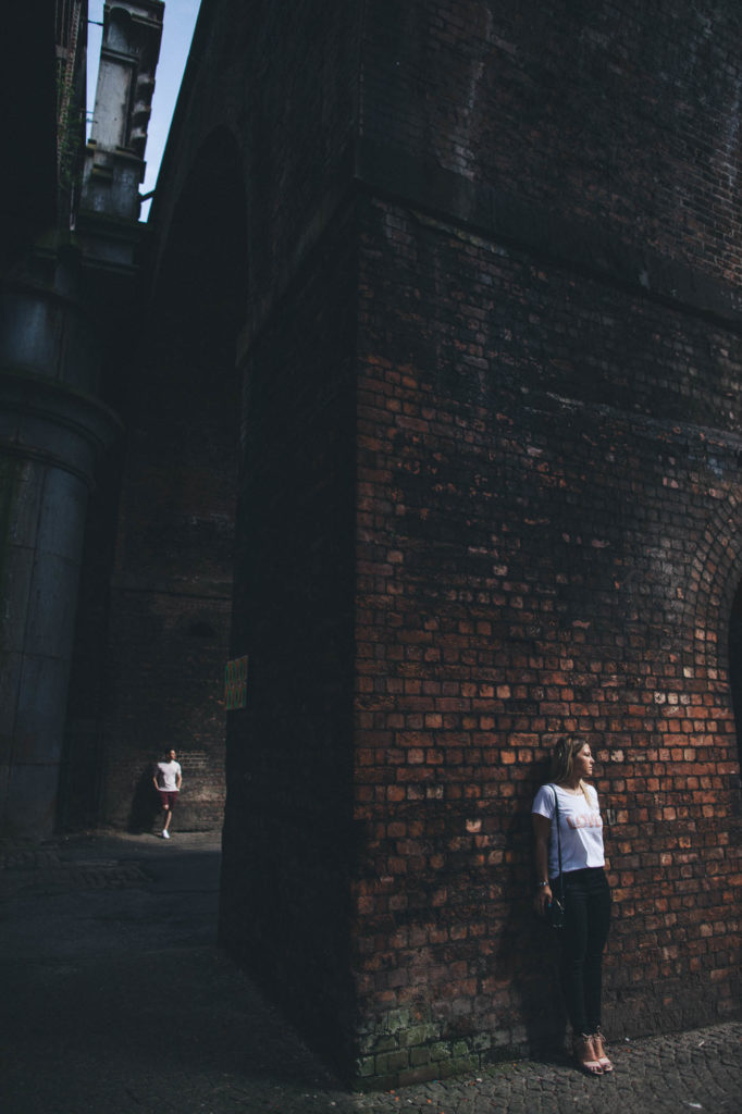 couple pose separately in great light in bricked background industrial scene