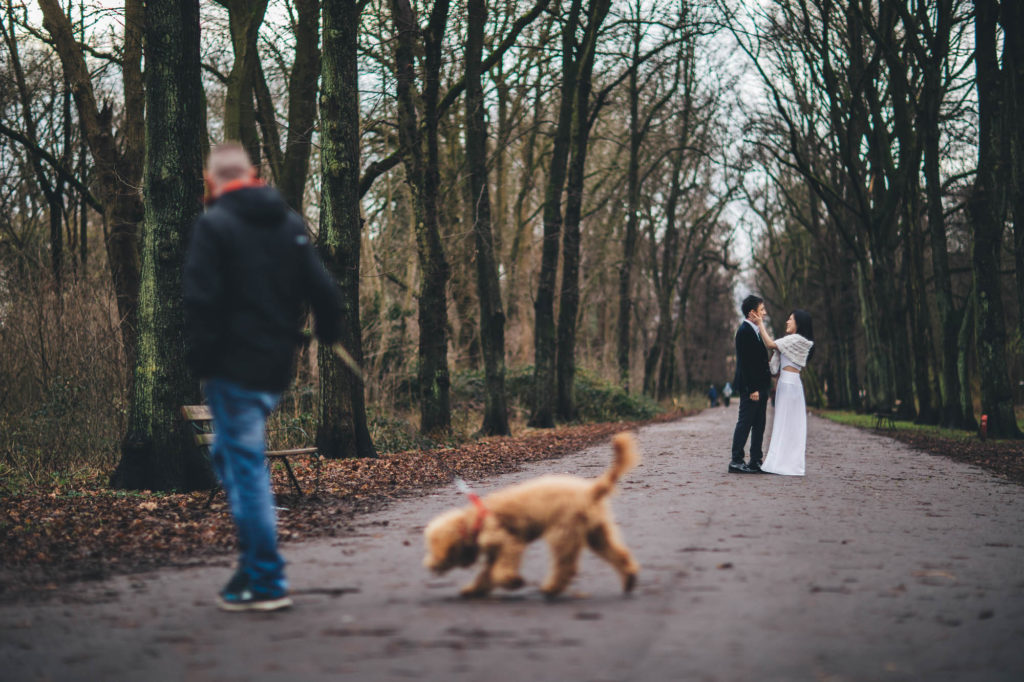 couple embrace while man walks his dog in the foreground