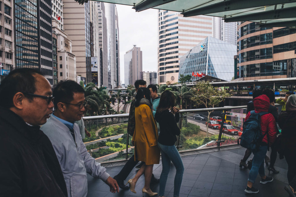 street photography photo in hong kong. offcie workers walking the streets in the foreground