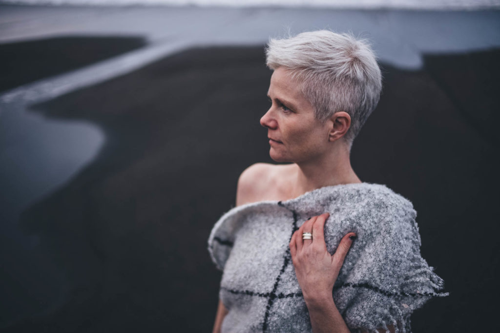 posing under a blanket on a black sand beach