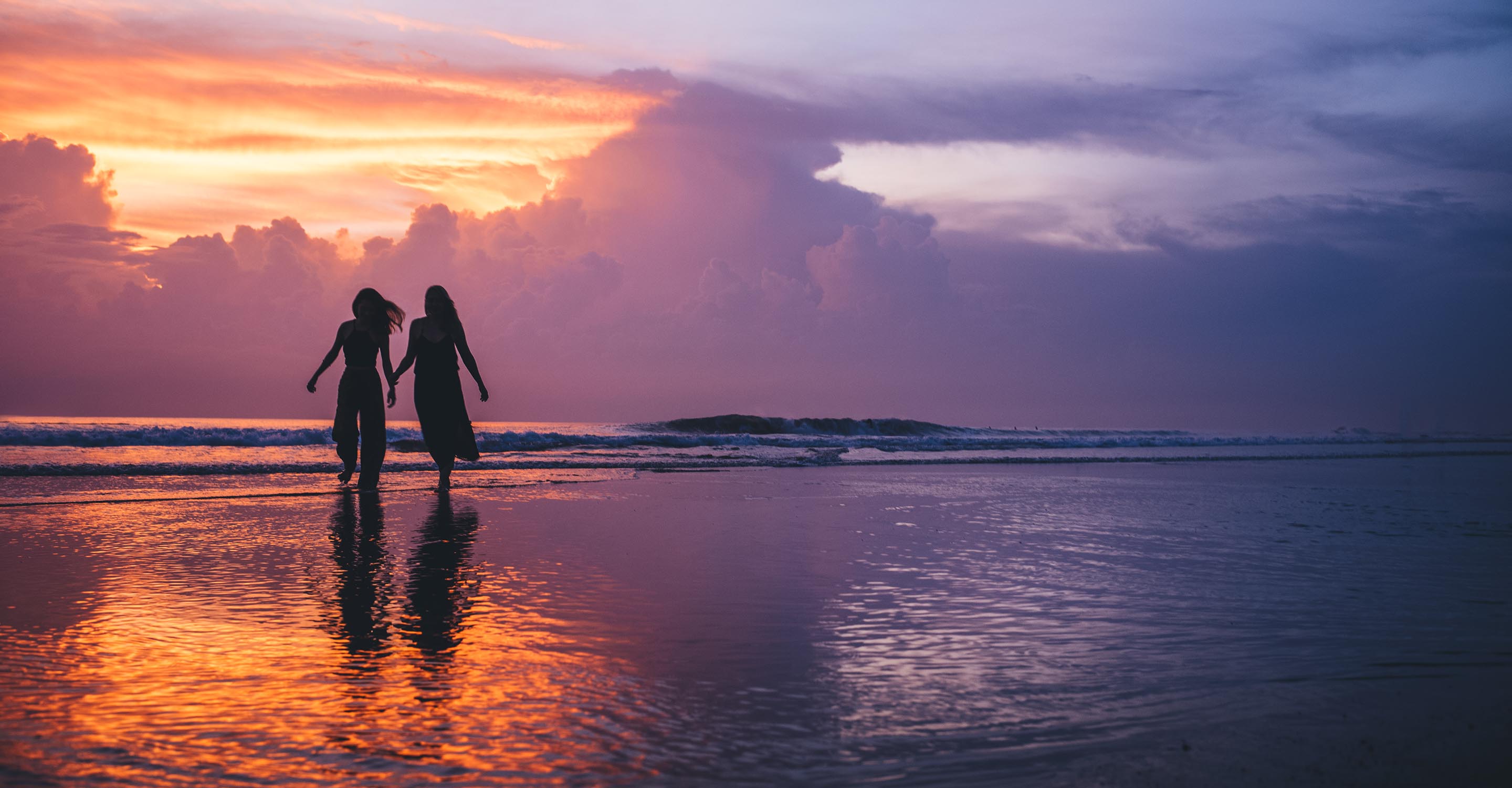 couple hold hands on the beach at sunset