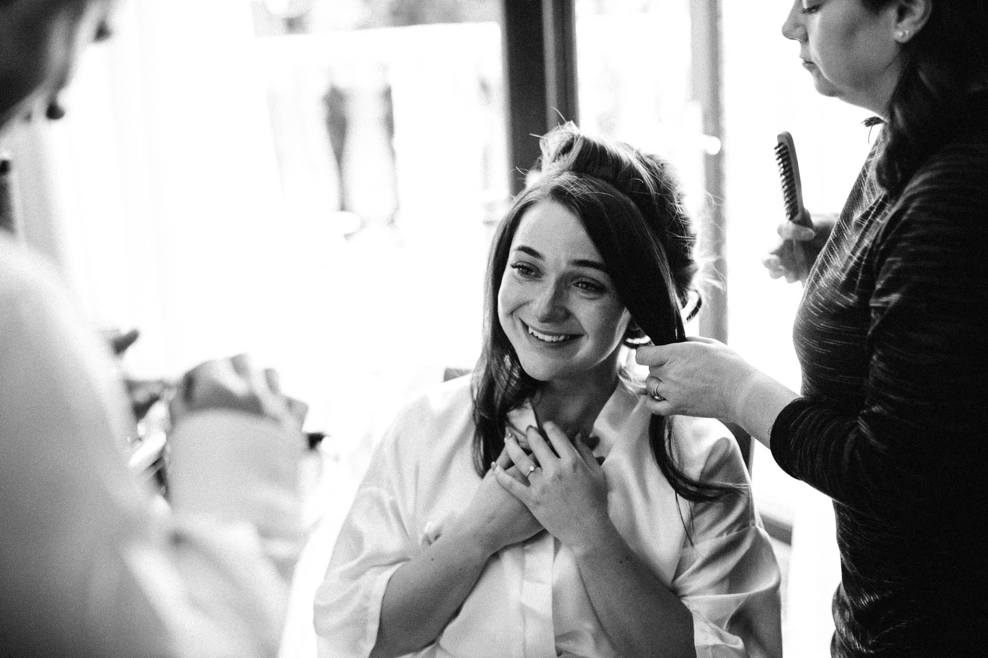Bride having her hair done during bridal preparations and looking emotional