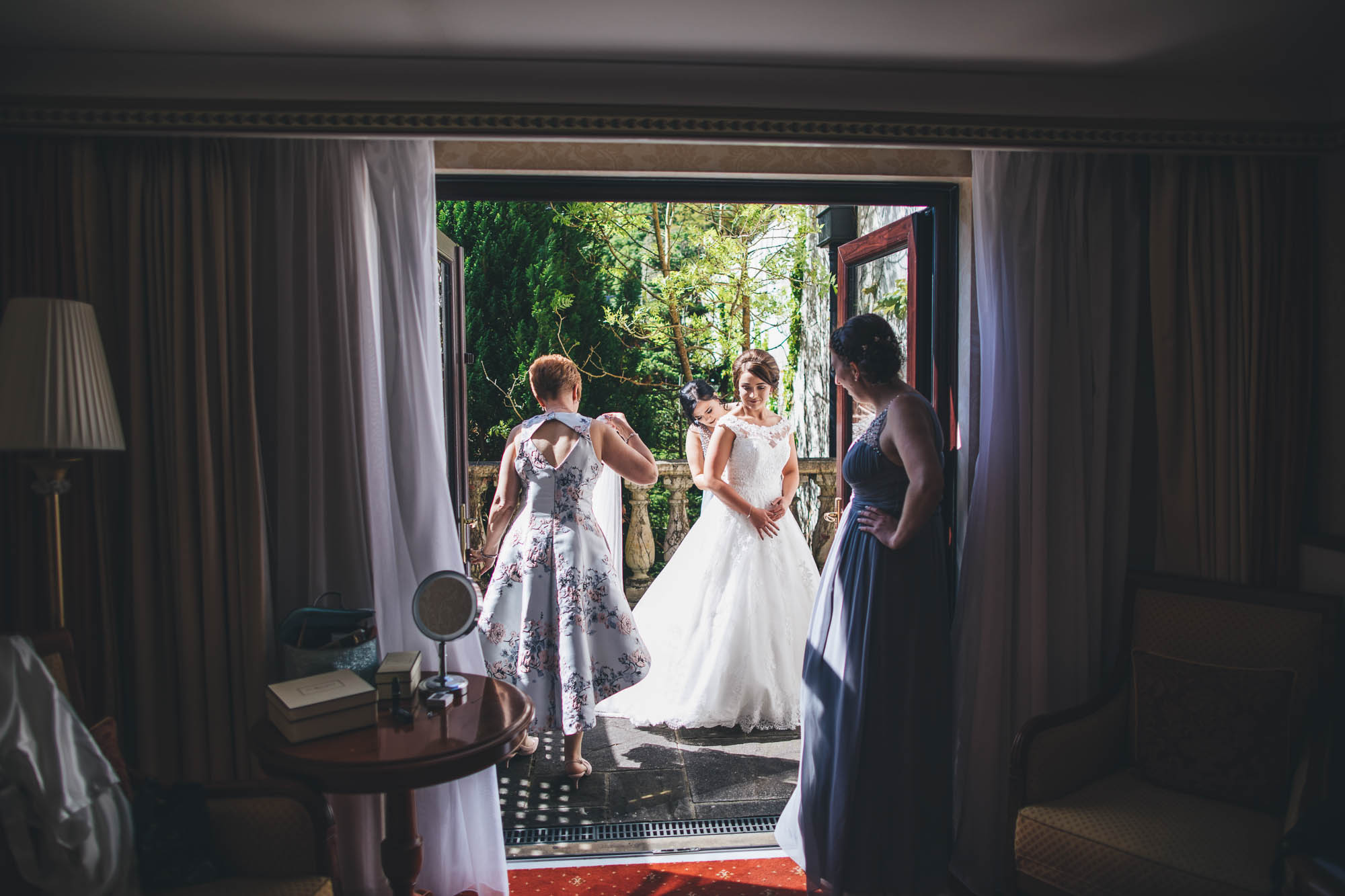 Wide shot looking outside to Bride and her Bridal party making adjustments before wedding ceremony