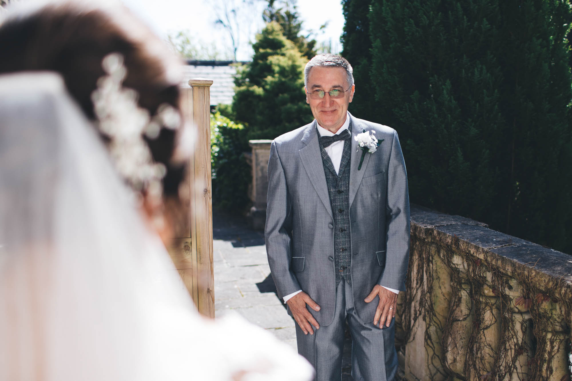 Back of Brides head out of focus in foreground to draw attention to Father of Bride seeing his daughter on wedding day for the first time