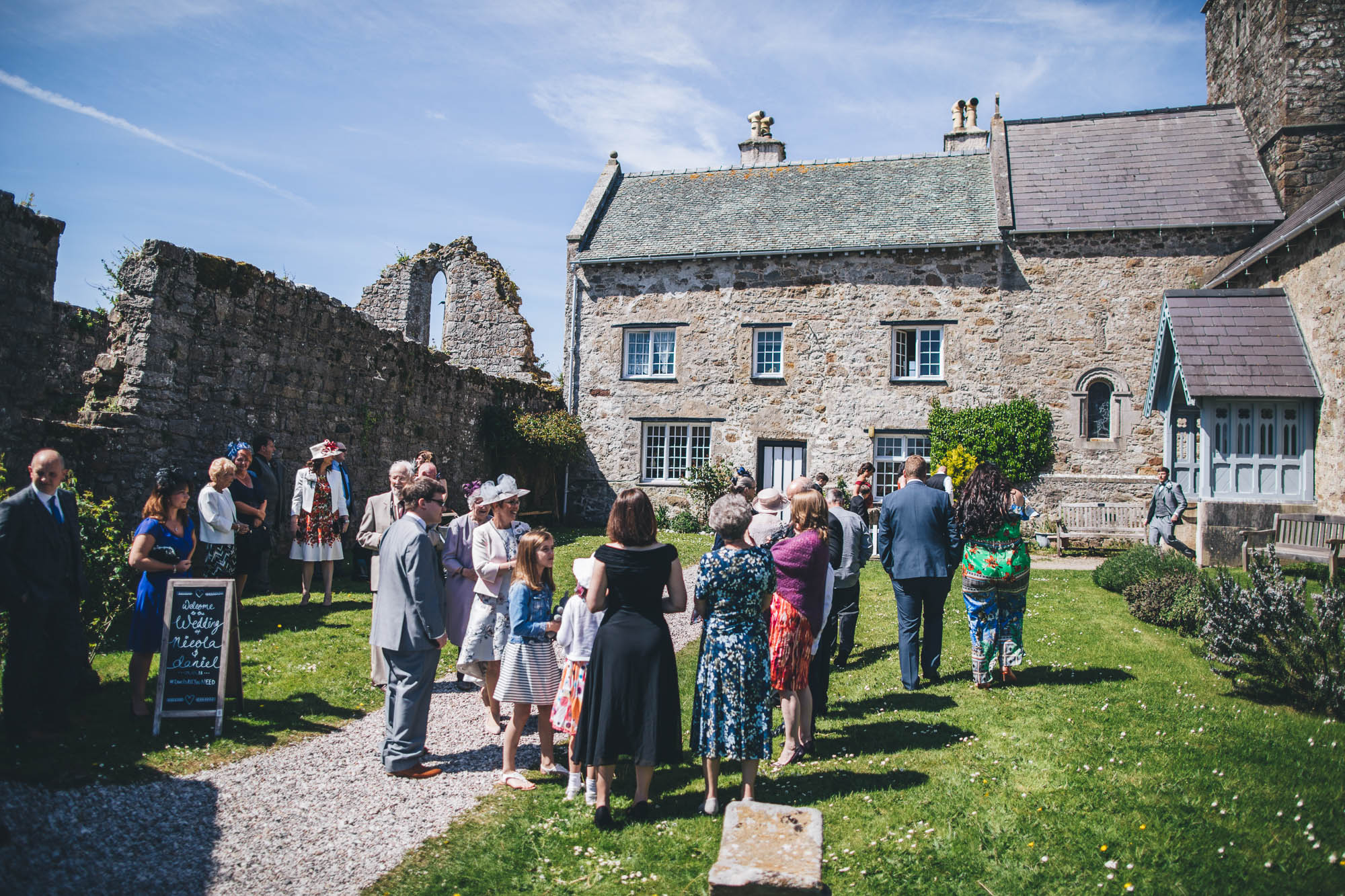 Wedding Guests arrive outside historic Anglesey Church in Penmon on beautiful sunny day