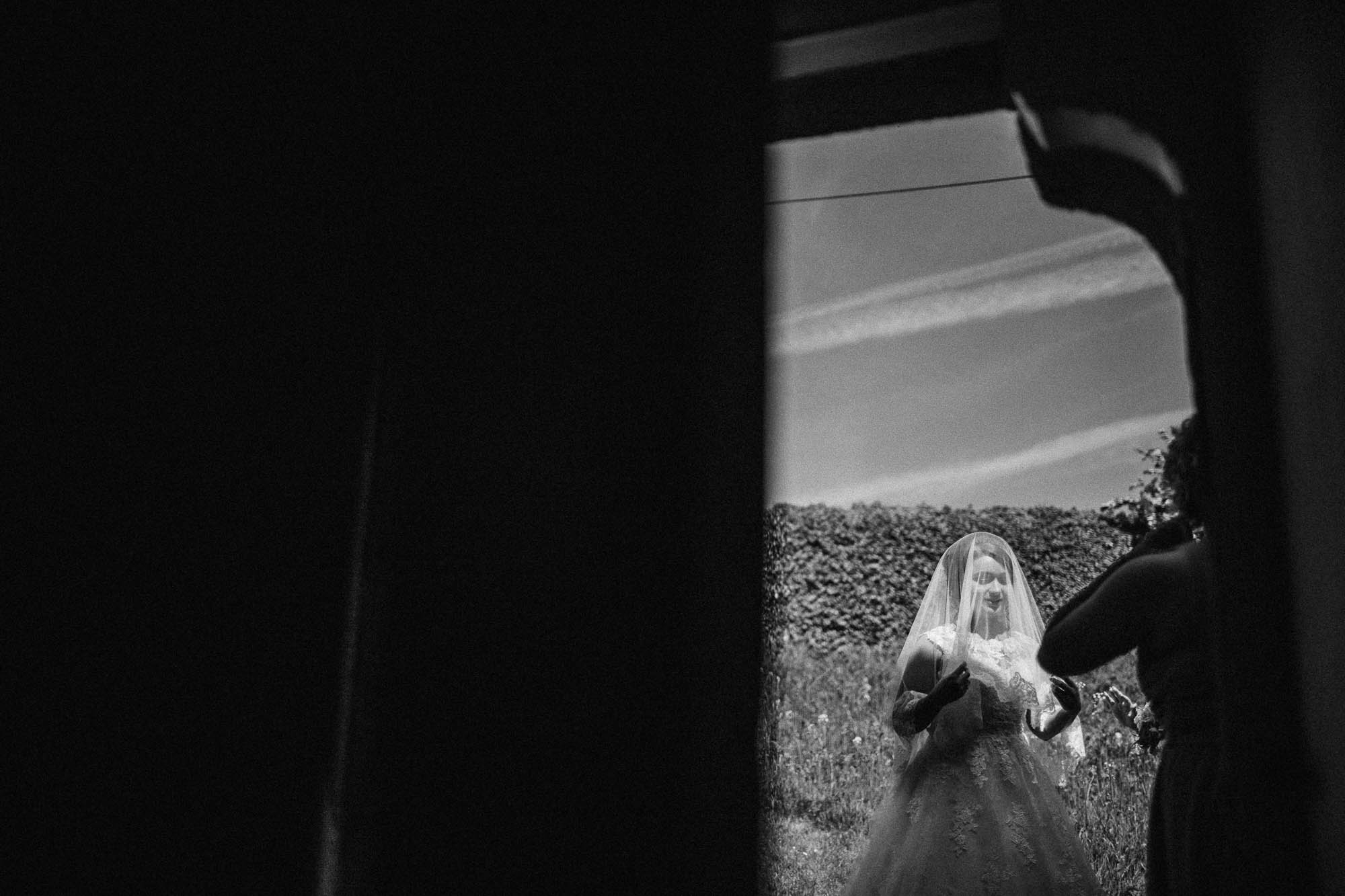 Black and white shot of veiled Bride on her way into the church