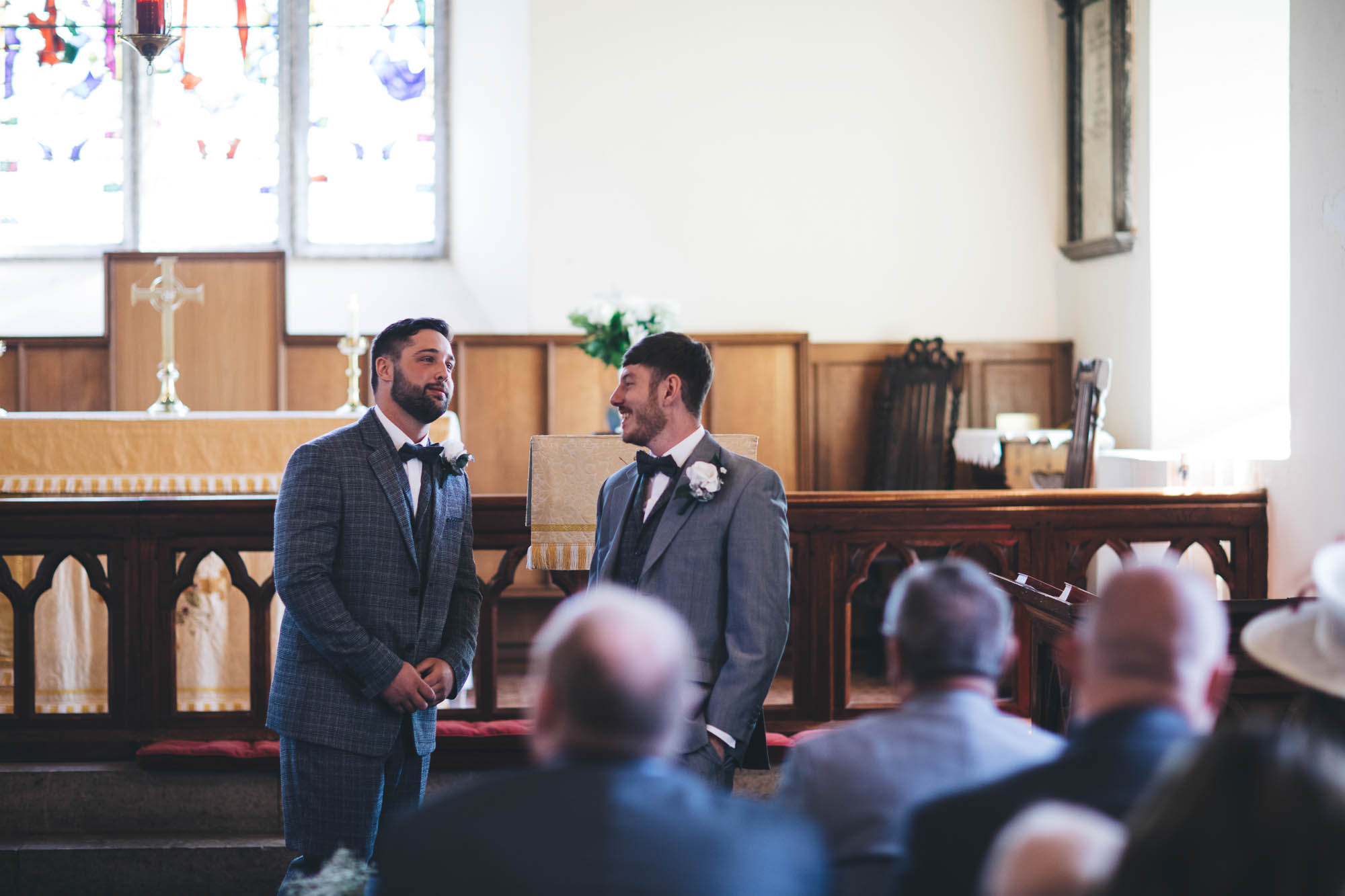 Groom and Best Man share a joke at the altar before the wedding ceremony starts