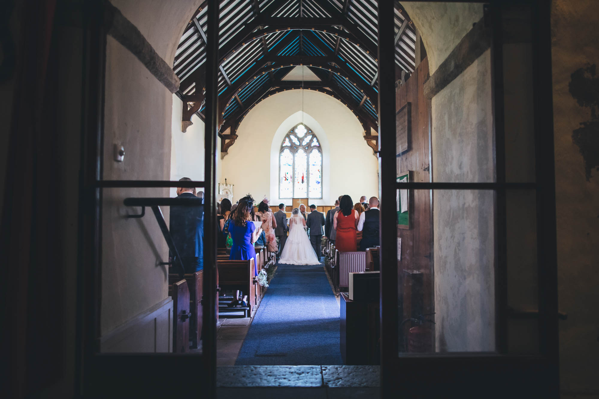 Shot of wedding ceremony taken from back of historic Anglesey church in Penmon