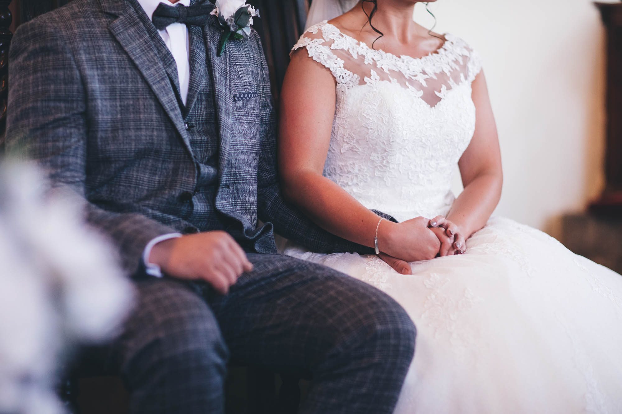 Close up shot of Bride and Groom sat down holding hands at wedding ceremony