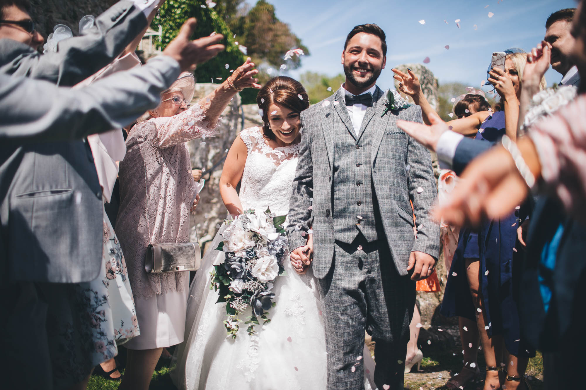 Smiley Bride and Groom are showered with confetti and greeted with cheers as they leave the church as a married couple for the first time