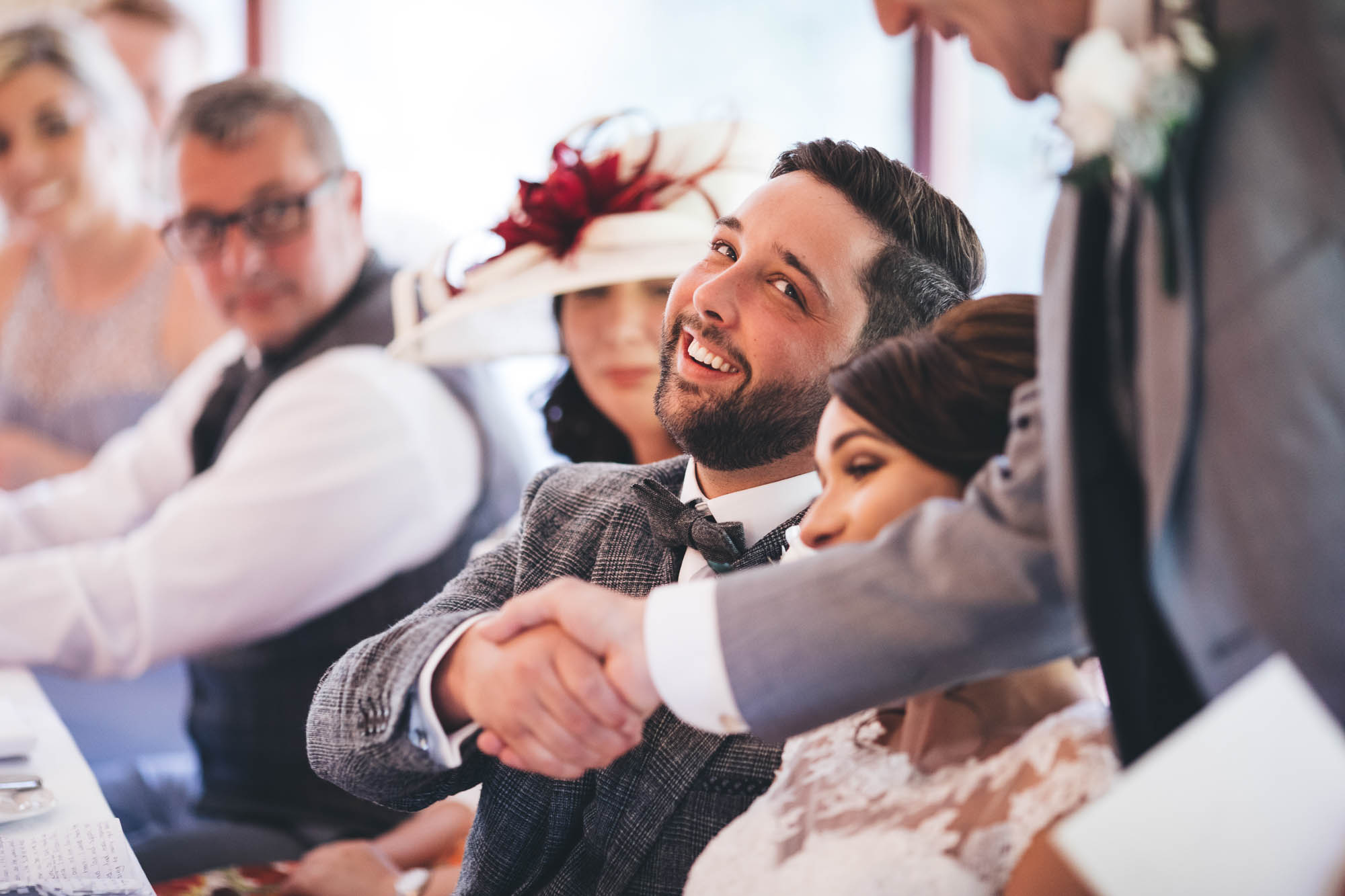 Groom shakes hand with Father of Bride during speech at top table