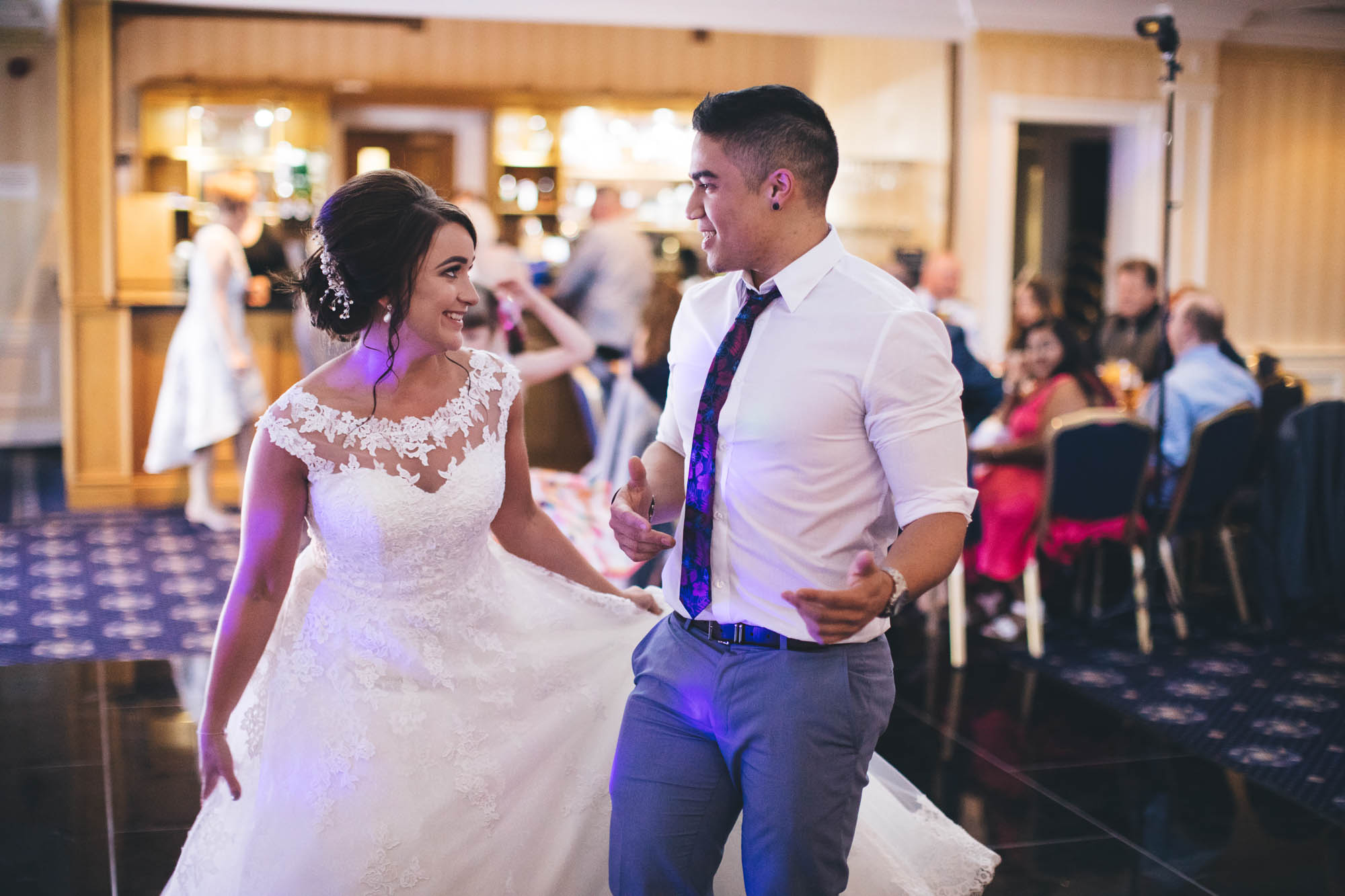 Bride and guest share a smile while they dance on the dance floor at wedding disco
