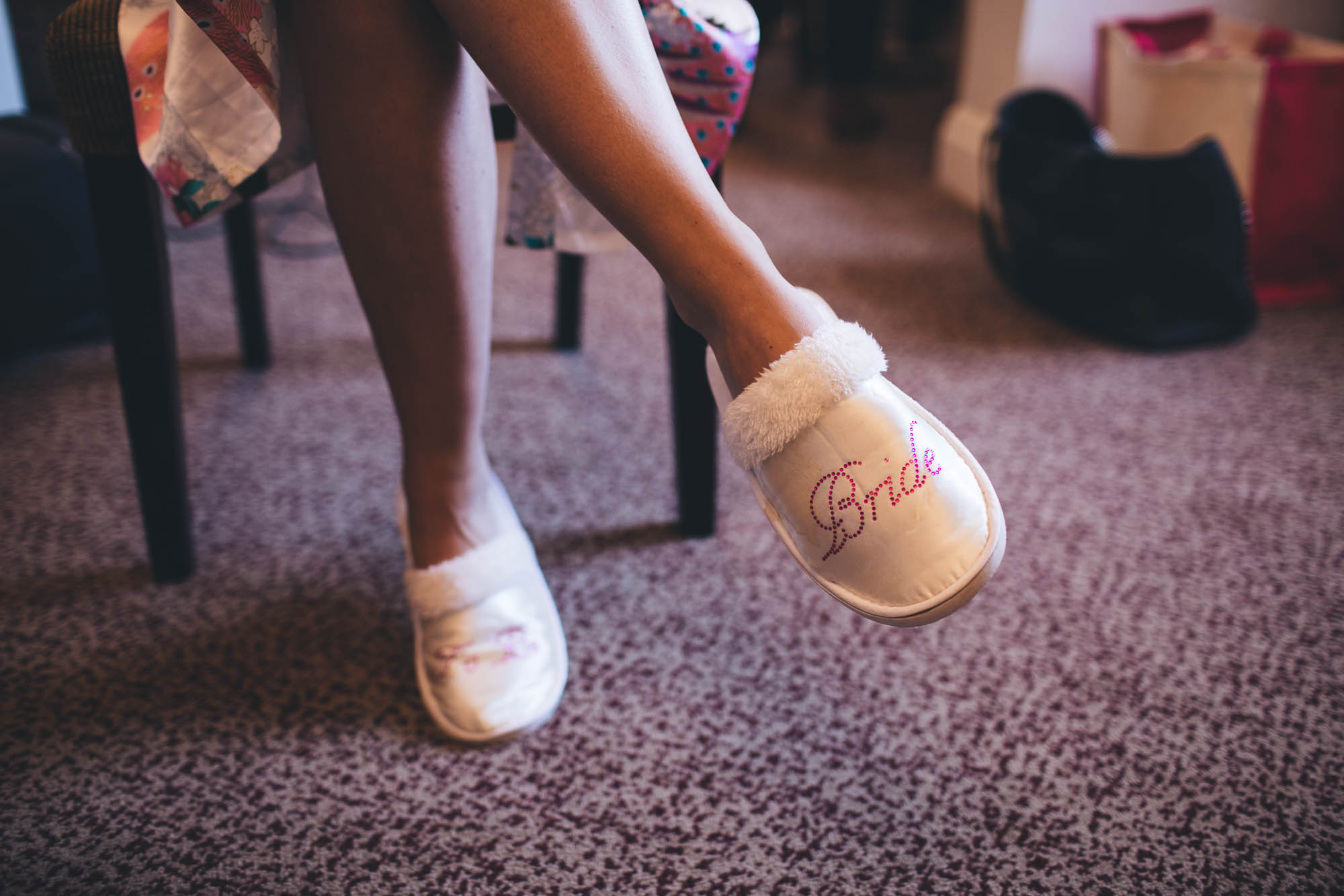 Close up shot of brides feet wearing special slippers that say bride during bridal preparations