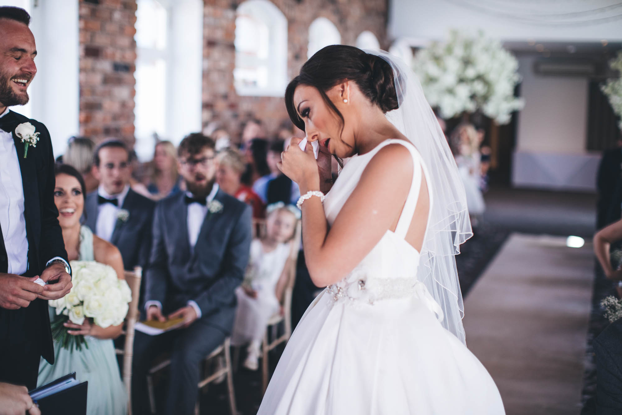 Bride wipes tears as she arrives at wedding altar