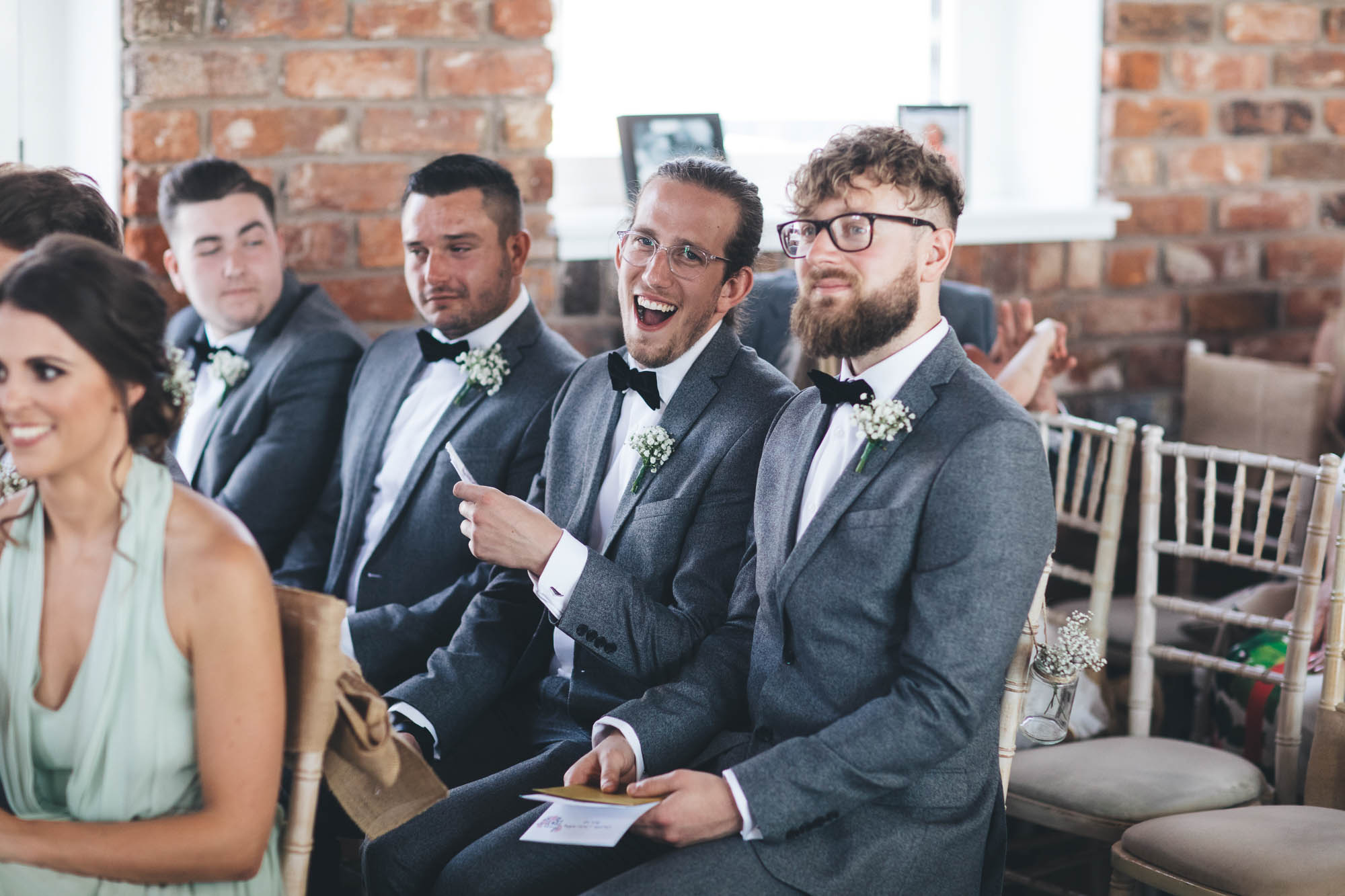 Groomsmen laugh and joke during the ceremony