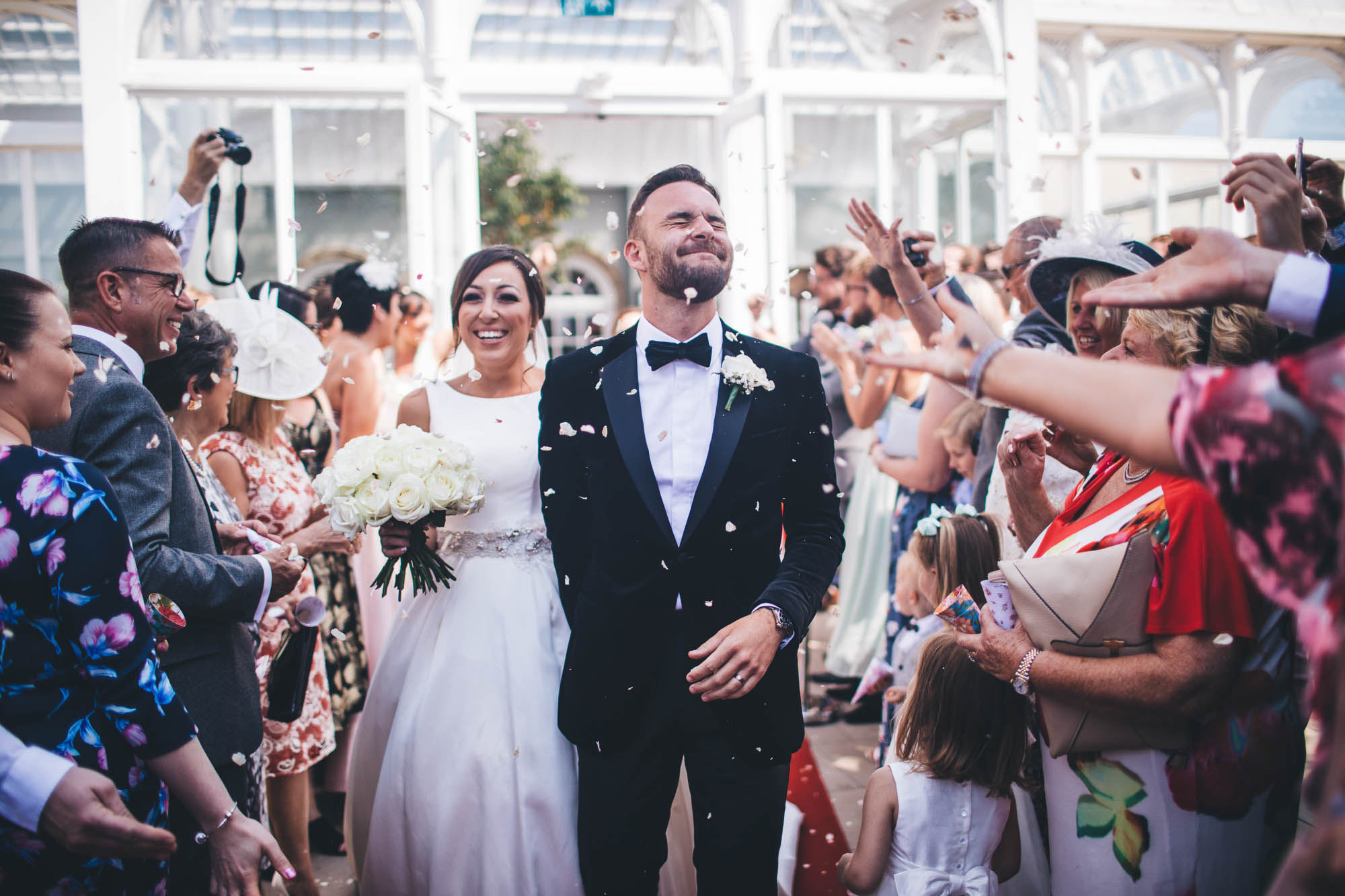 Guests throw confetti at newlyweds as they leave the wedding ceremony