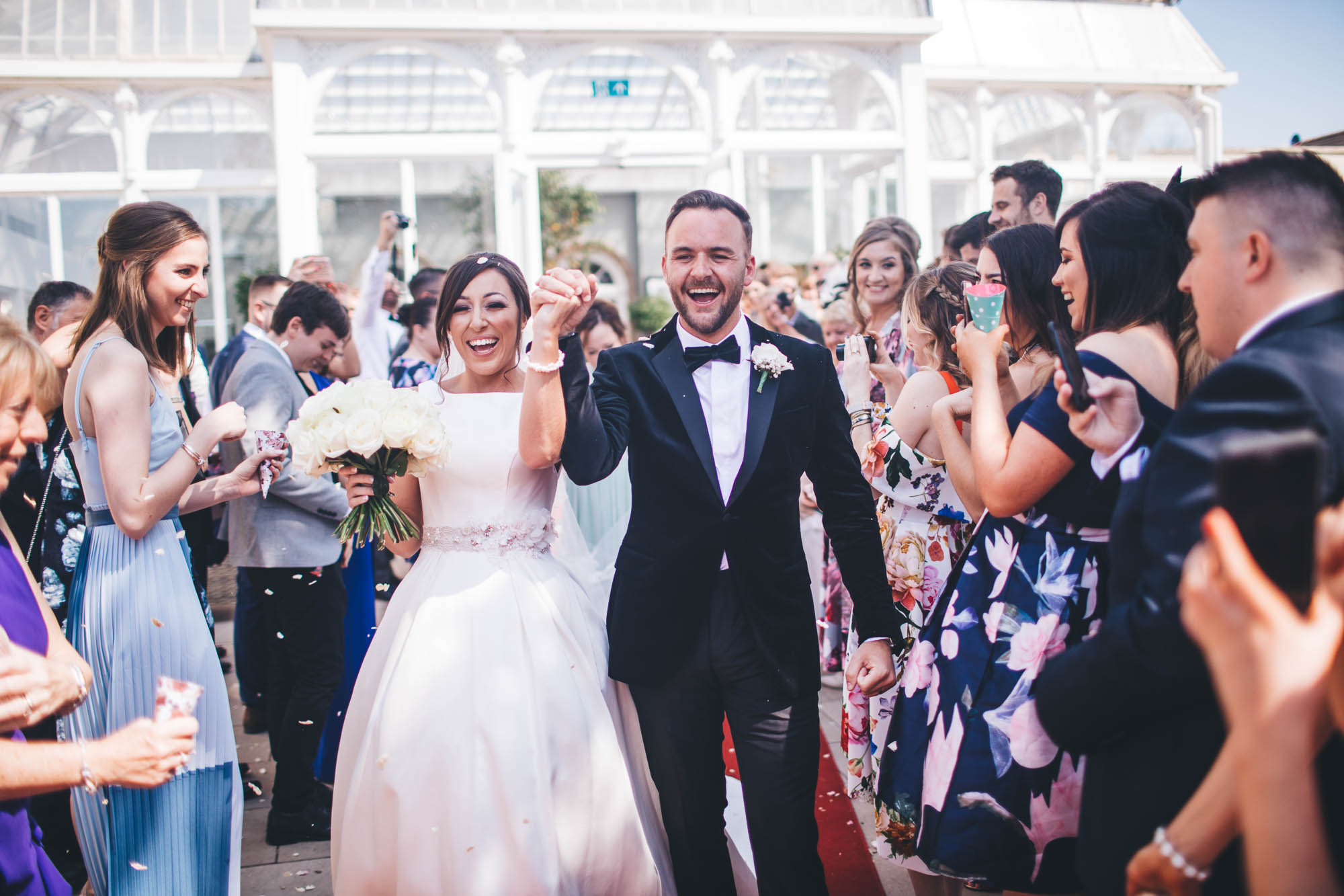 Newlyweds smile with glee as they leave the wedding venue