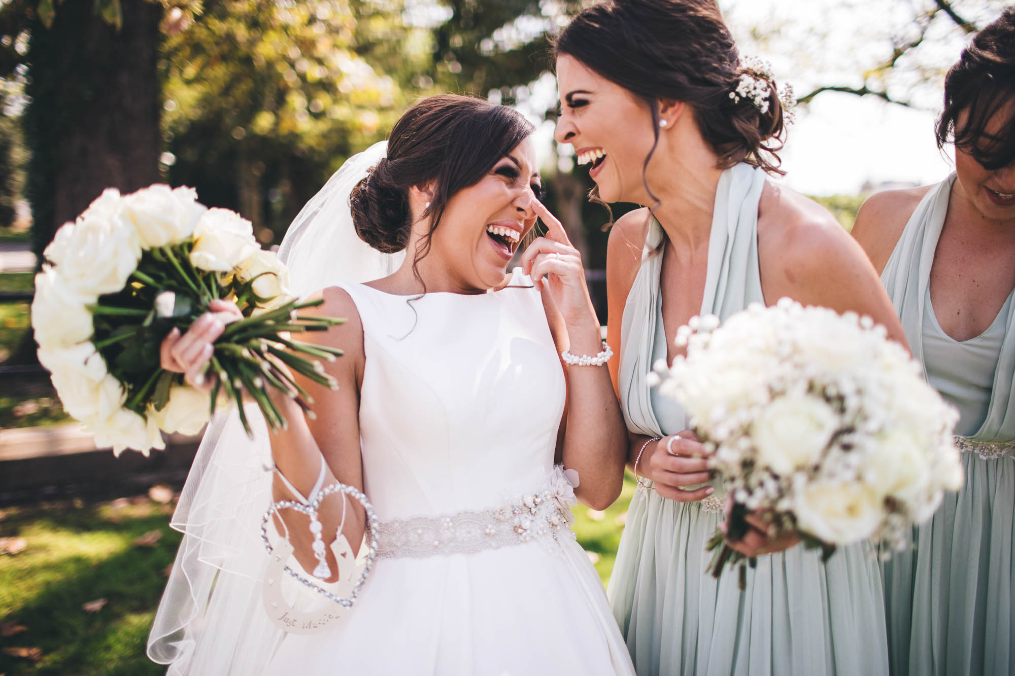 Bride and Maid of Honour laugh with each other outside on a sunny day