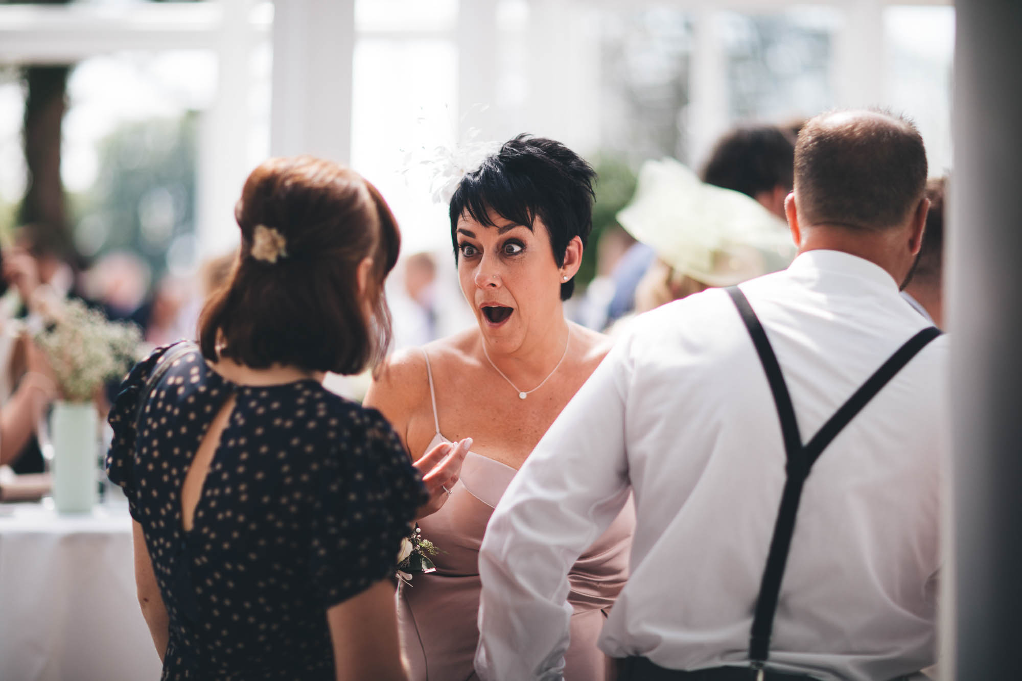 Wedding guest looks shocked and overjoyed after being told something fantastic