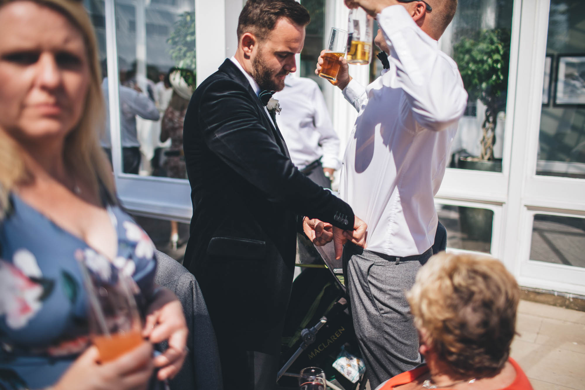 Groom tucks Usher shirt in while he holds two drinks