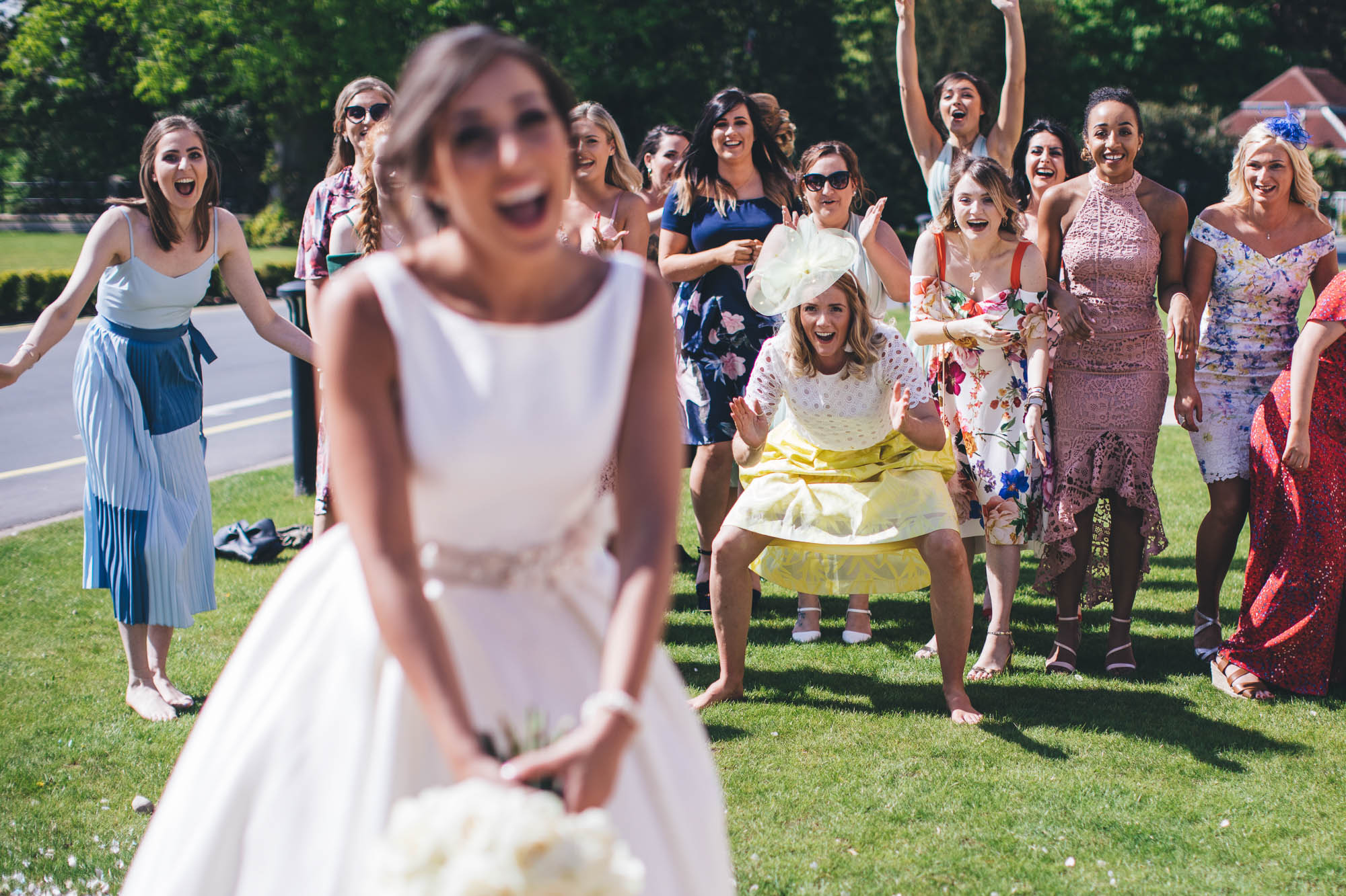 Bride prepares to throw flowers as wedding guests prepares to catch the wedding bouquet