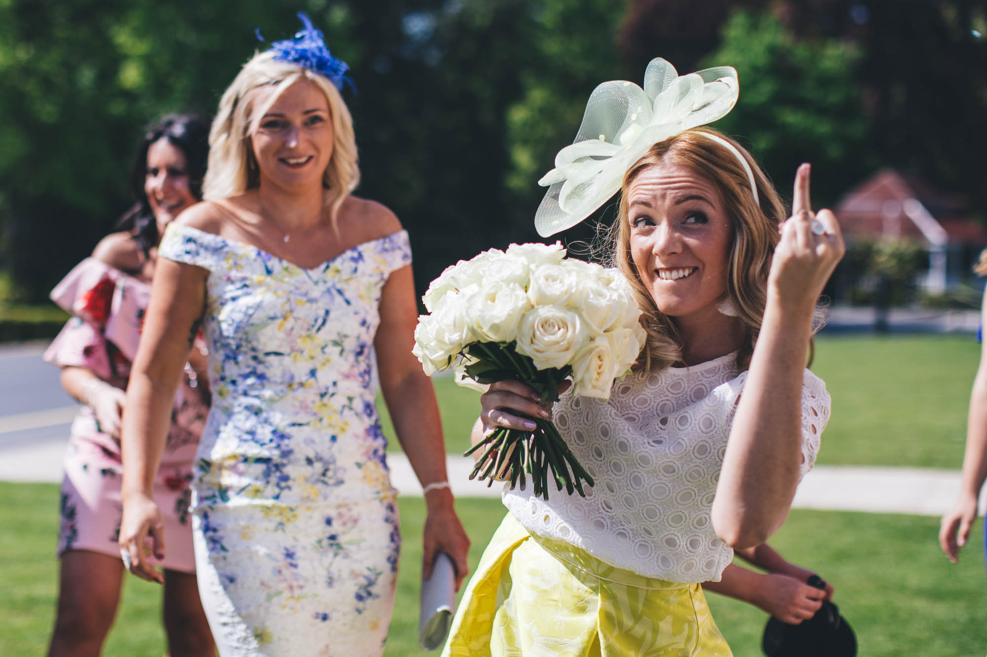 Wedding guest who has caught bride bouquet gestures to boyfriend to put a ring on her engagement finger