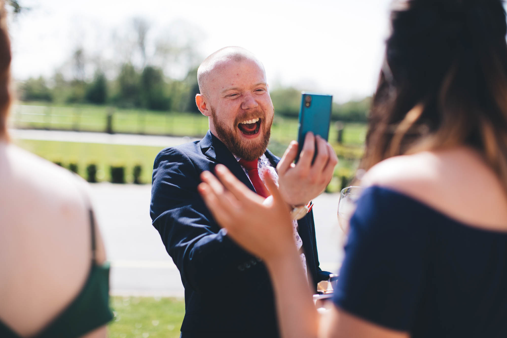 Wedding guest takes a funny photo on his phone of another guest