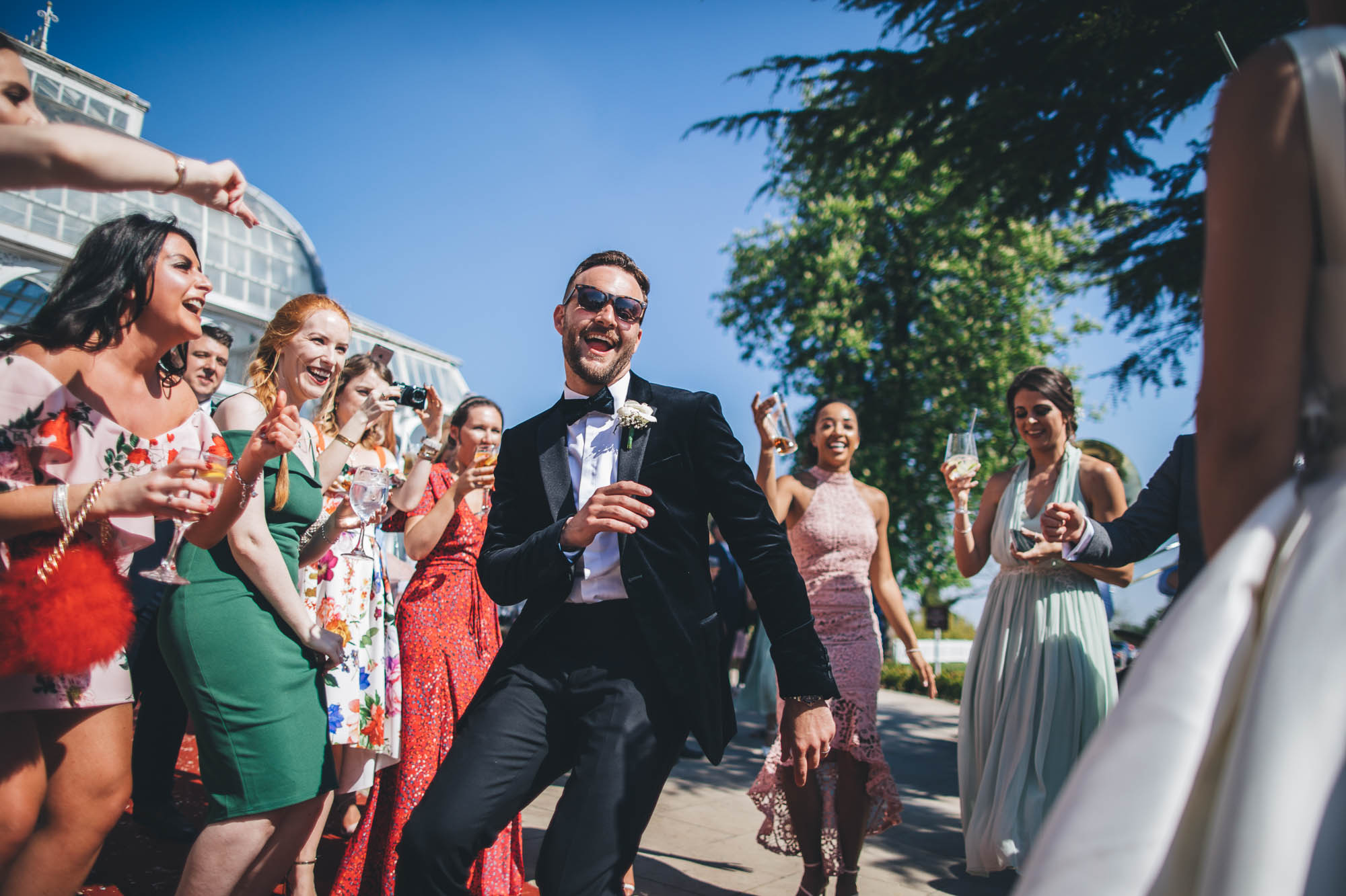 Groom shows off his dance moves outside in front of wedding guests and Bride
