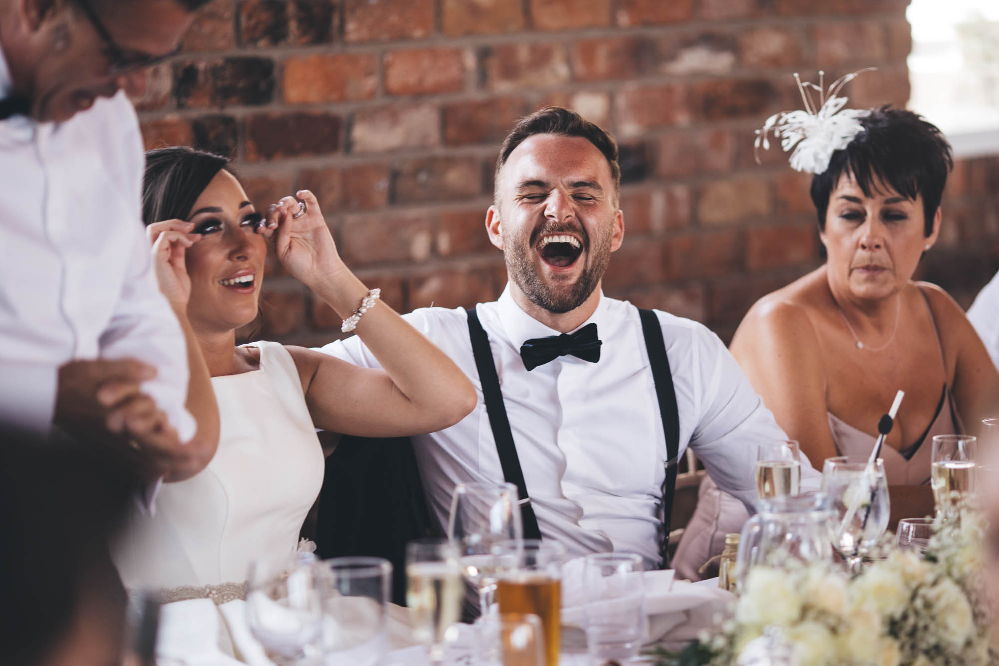 Groom roars with laughter during father of the bride speech and Bride wipes her tears