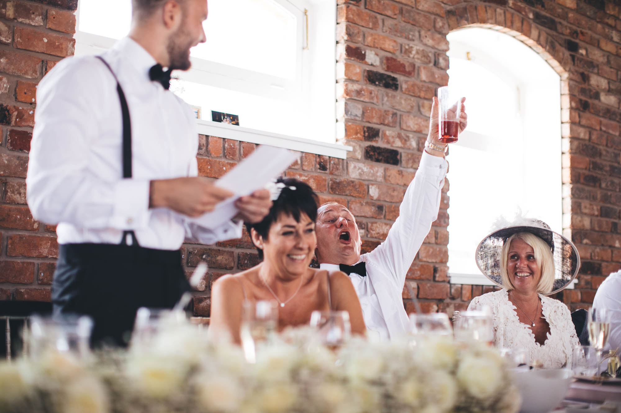 Father of Groom raises his glass enthusiastically as Groom gives speech