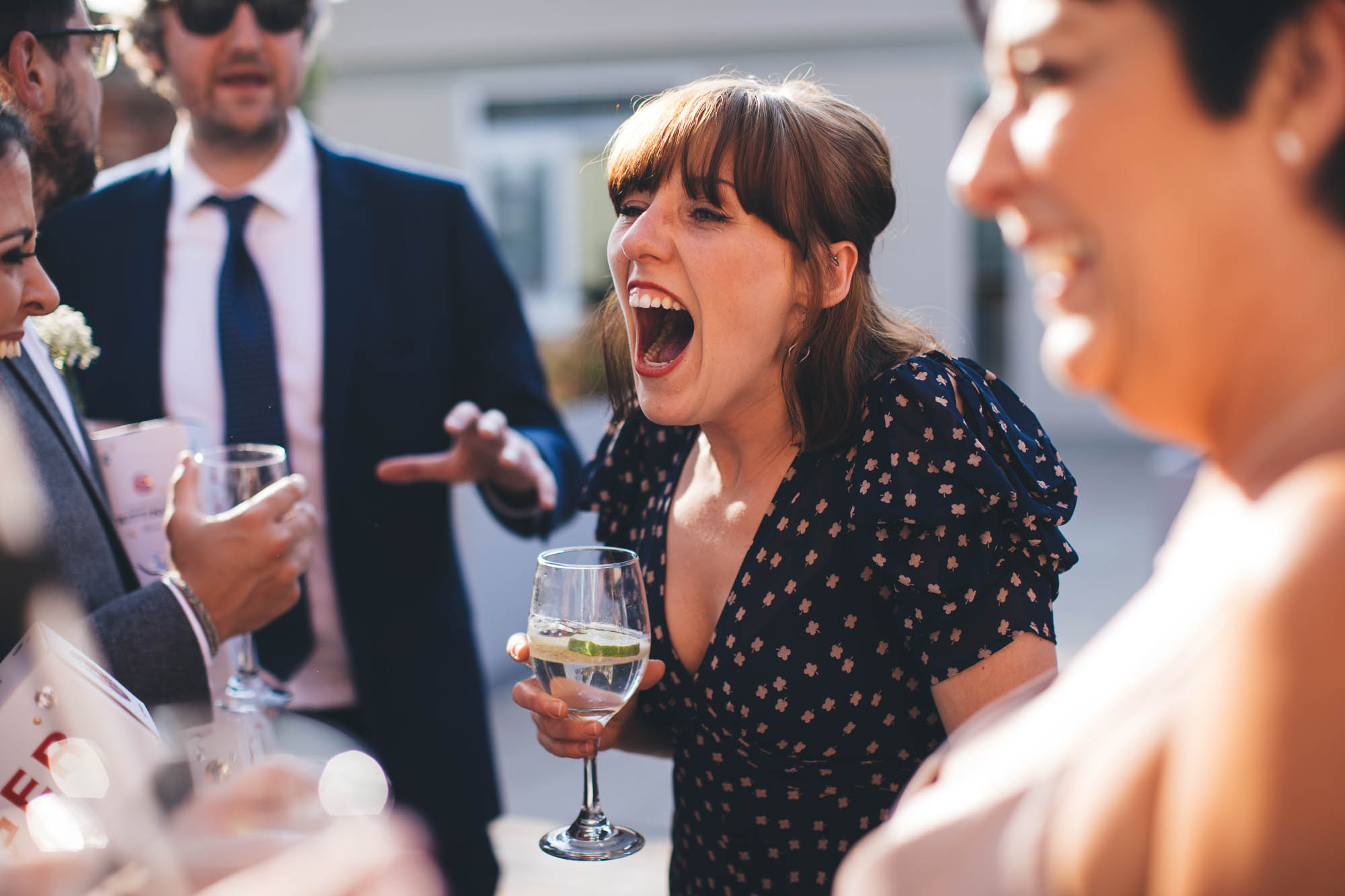 Wedding guest laughs at a joke outside during receptions drinks