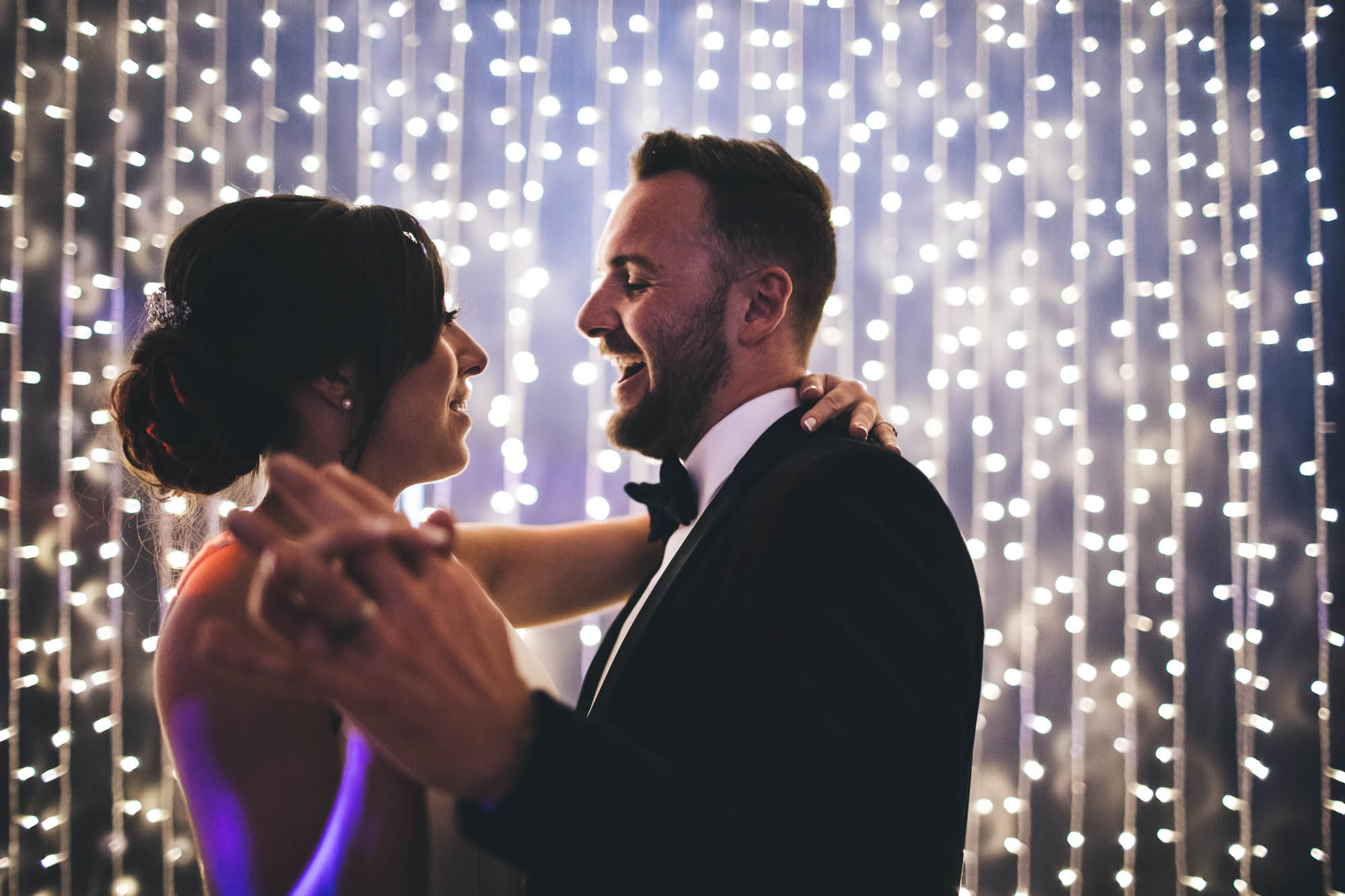 Married couple share first dance in front of fairy lights